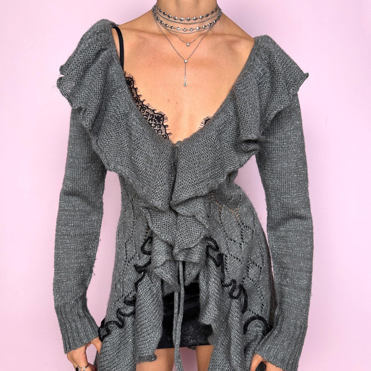 This romantic vintage 2000s gray longline open-knit cardigan features a dramatic ruffle neckline, ruffled hem, and a tie-front closure. The soft, draped silhouette and textured open-knit pattern create a whimsical coquette feel, ideal for autumn layering, winter fairycore styling, or cozy everyday outfits. Made from a stretchy acrylic and mohair blend. Great vintage condition.