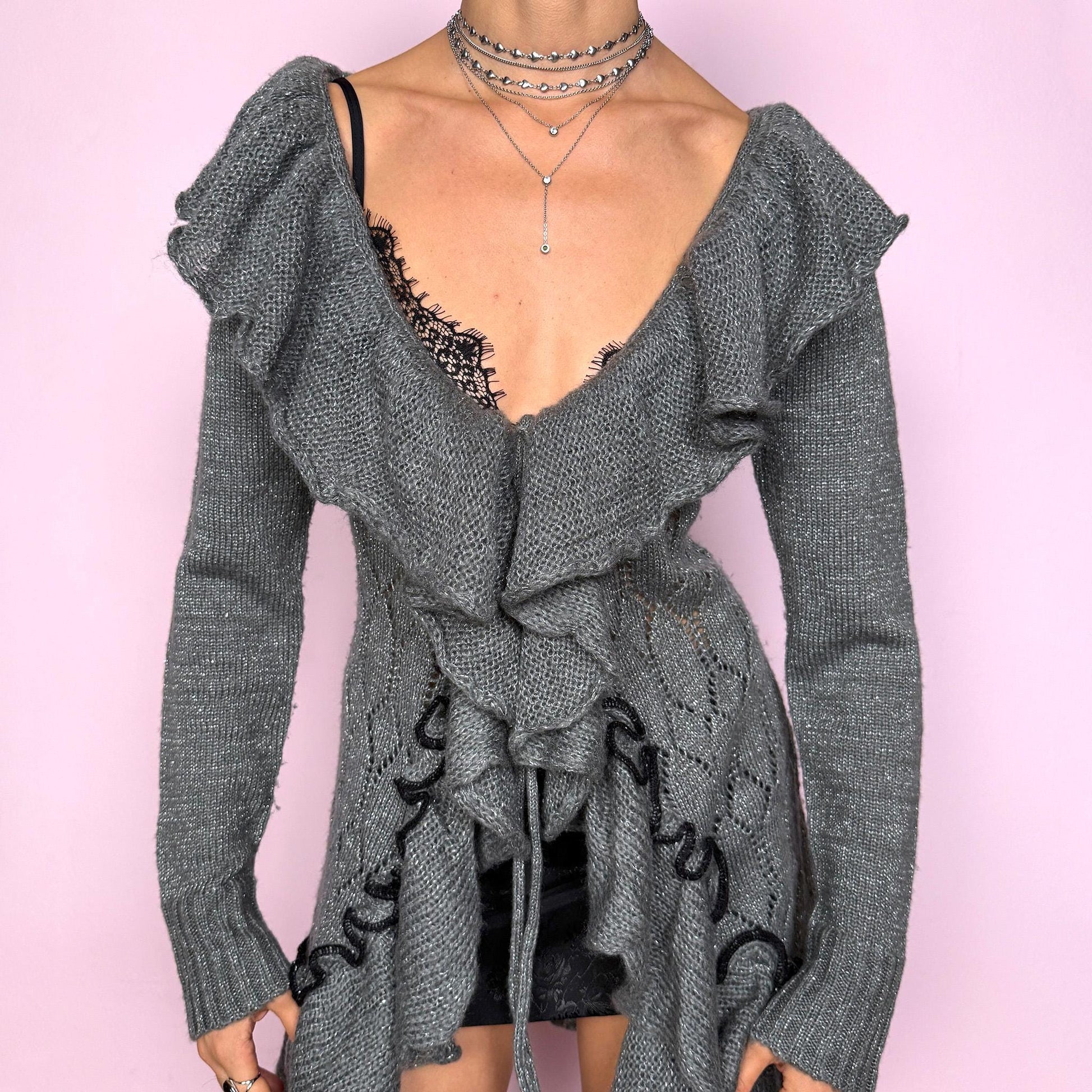 This romantic vintage 2000s gray longline open-knit cardigan features a dramatic ruffle neckline, ruffled hem, and a tie-front closure. The soft, draped silhouette and textured open-knit pattern create a whimsical coquette feel, ideal for autumn layering, winter fairycore styling, or cozy everyday outfits. Made from a stretchy acrylic and mohair blend. Great vintage condition.