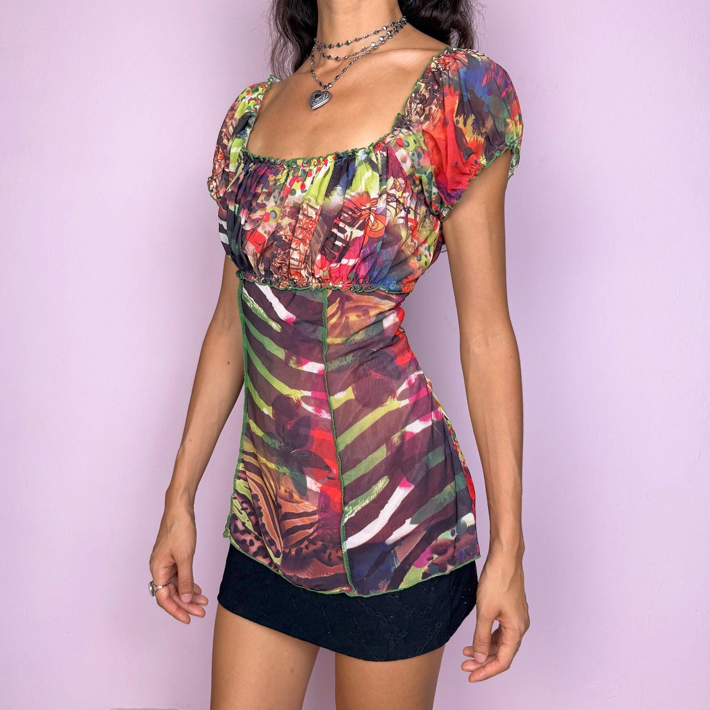 Vintage 2000s vibrant and colorful mesh top with a sheer abstract graphic print and a ruched bust. Features short puff sleeves, contrast seams, and a stretchy fitted silhouette that creates a bold statement look. Perfect for party nights, summer festivals, and weird-girl or cyber-inspired styling. Excellent vintage condition.