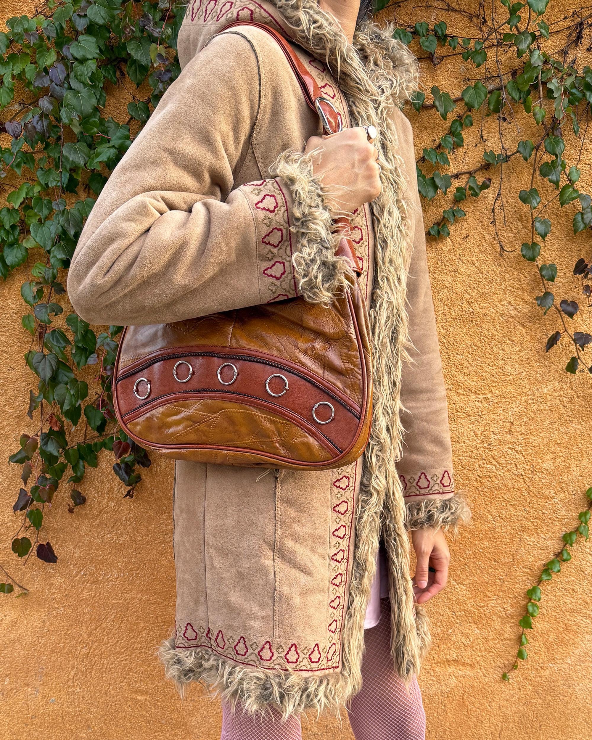 Vintage 2000s brown and mustard-brown faux leather shoulder bag with classic Y2K city-girl appeal. Features metal O-ring details across the front, contrast paneling, and a secure double zip closure. The slouchy silhouette makes it perfect as a bold 2000s statement everyday bag or a party-night accessory. Excellent vintage condition.