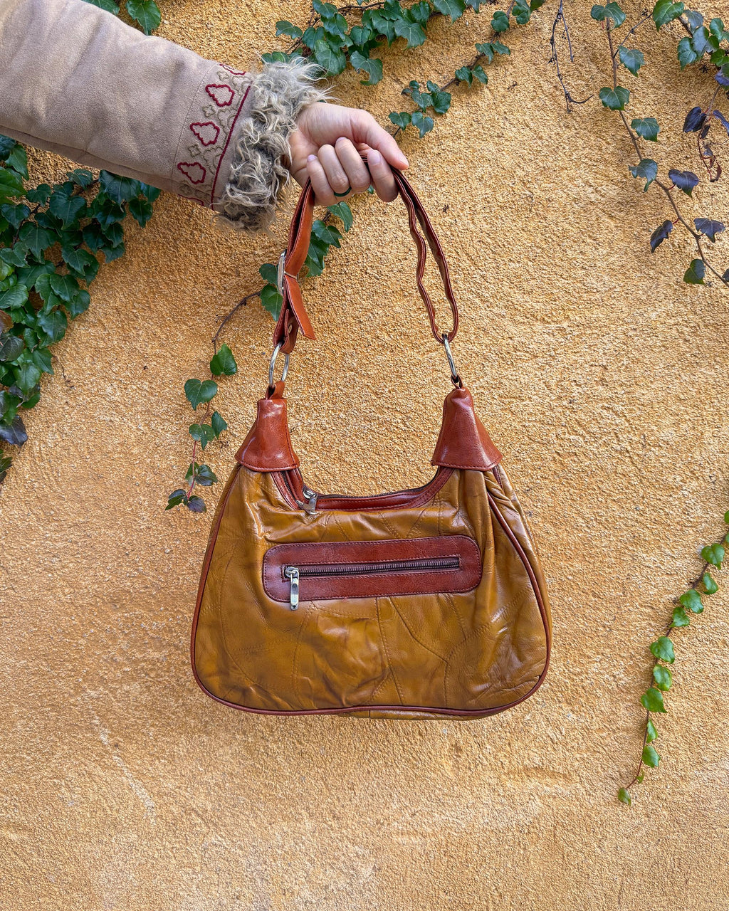 Vintage 2000s brown and mustard-brown faux leather shoulder bag with classic Y2K city-girl appeal. Features metal O-ring details across the front, contrast paneling, and a secure double zip closure. The slouchy silhouette makes it perfect as a bold 2000s statement everyday bag or a party-night accessory. Excellent vintage condition.