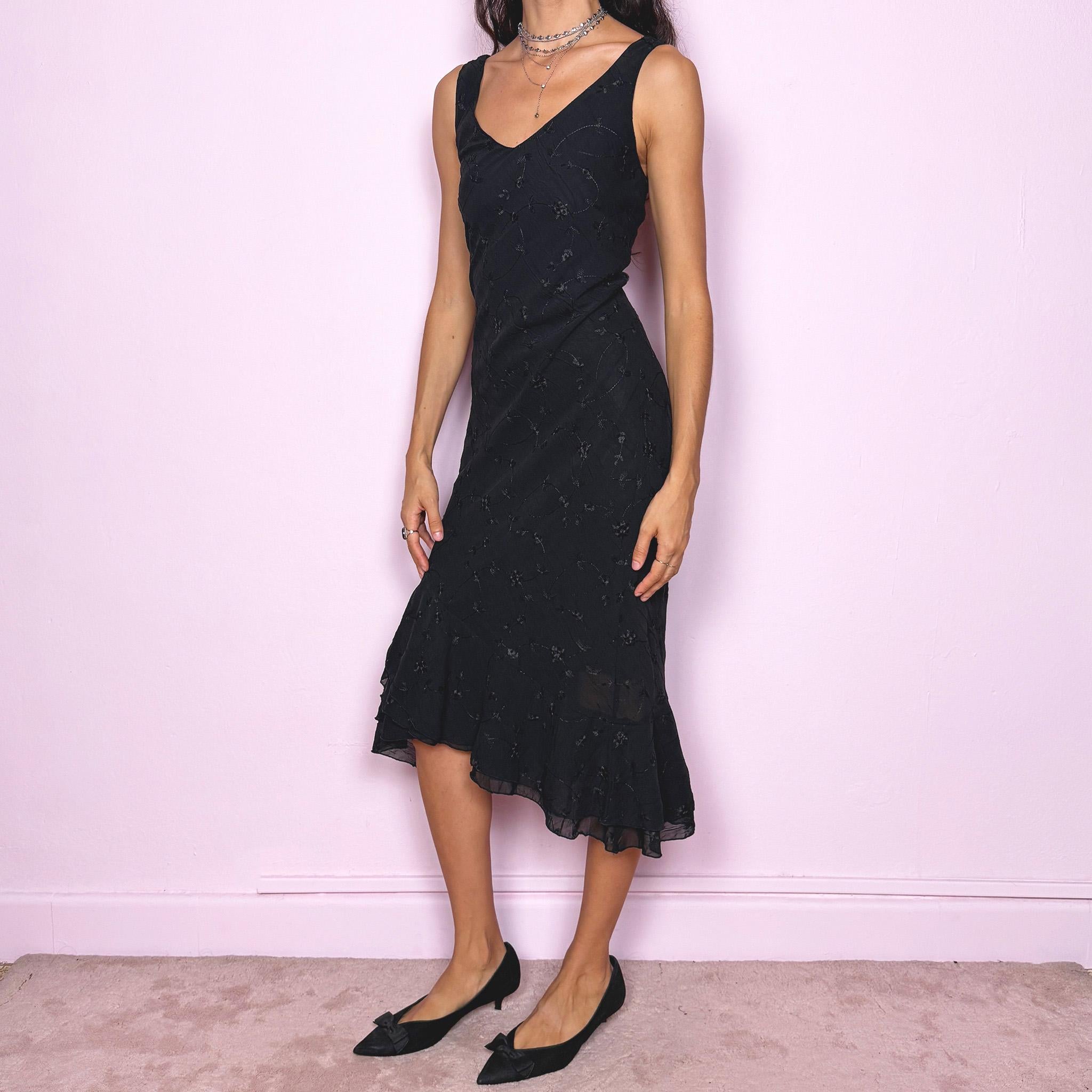 Romantic vintage 2000s black midi dress featuring delicate floral embroidery, a sleeveless cut, a V-neckline and an asymmetrical layered ruffle hem. The slightly stretchy fabric offers a comfortable, flattering fit with a minimal yet elegant look, perfect for a summer night event. Made in Spain from polyester. Excellent vintage condition.