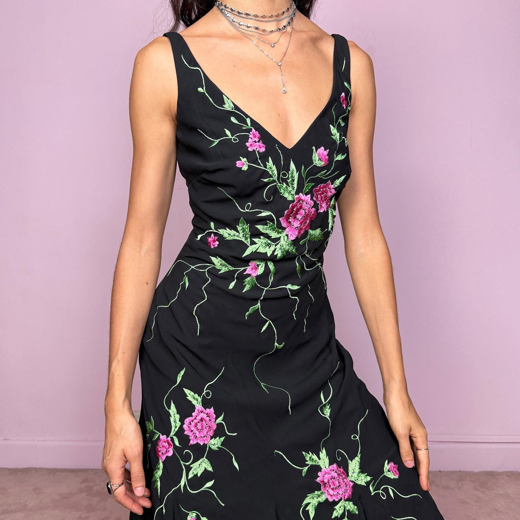 Stunning vintage 2000s black sleeveless V-neck long midi dress featuring pink and green floral embroidered details with beaded accents. The asymmetric handkerchief-style hem adds movement and a romantic statement look, perfect for gala events, formal parties or night occasions. Made from polyester. Excellent vintage condition.