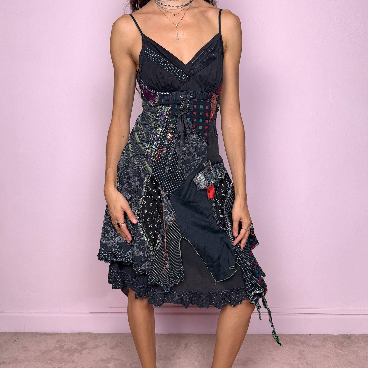 Whimsical and unique vintage 2000s dark-gray washed-black V-neck midi dress featuring intricate patchwork appliqué in mixed prints. Designed with adjustable straps, a side zipper closure, a shirred elastic back and a lace-up tie detail on one side for an adjustable fit. The textured, deconstructed look creates a witchy rag-doll, weird-girl aesthetic ideal for goth parties or statement nights out. Great vintage condition.