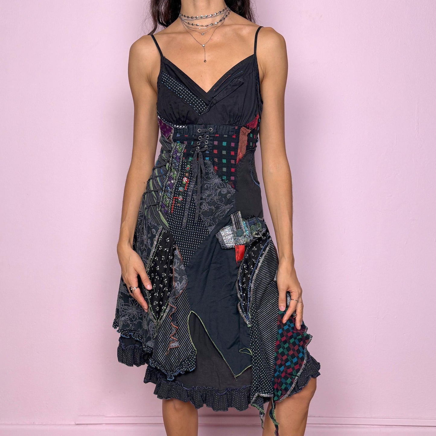 Whimsical and unique vintage 2000s dark-gray washed-black V-neck midi dress featuring intricate patchwork appliqué in mixed prints. Designed with adjustable straps, a side zipper closure, a shirred elastic back and a lace-up tie detail on one side for an adjustable fit. The textured, deconstructed look creates a witchy rag-doll, weird-girl aesthetic ideal for goth parties or statement nights out. Great vintage condition.