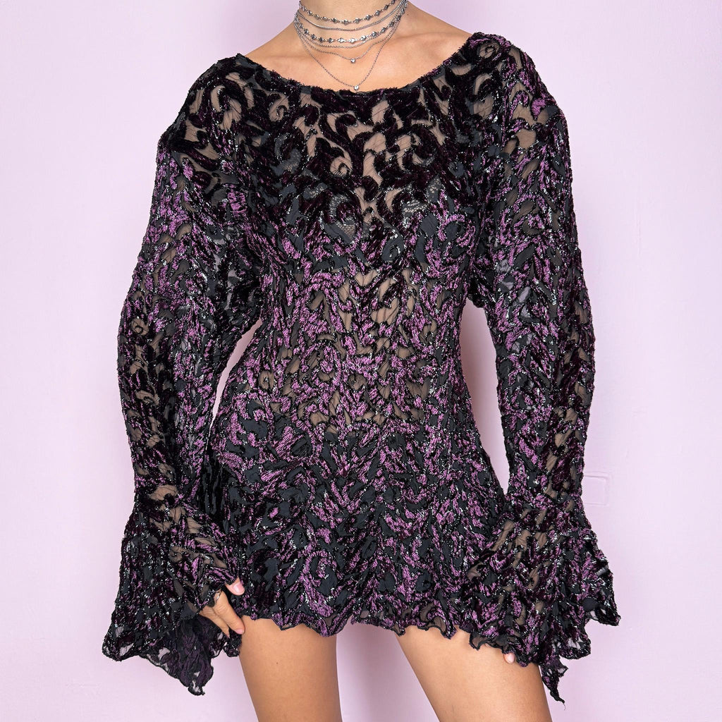 This vintage 2000s purple and black devoré velvet top delivers a dark romantic, witchy, goth aesthetic with a fitted bodice, sheer burnout pattern, metallic threads, asymmetric bell sleeves, and a flared hem. Ideal for evening styling, festivals, and statement layering. An archival French piece with a stretchy finish for comfortable wear. Excellent vintage condition.