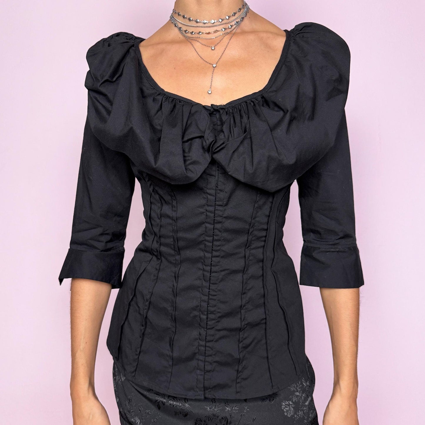 This dark avant garde vintage 2000s black blouse features a dramatic voluminous collared ruffle, a fitted pleated bodice, and three-quarter sleeves. Designed with a minimalist statement approach, it includes subtle mini hook closures and a slightly stretchy cotton–polyamide blend for a structured yet comfortable fit. The sculpted silhouette makes it ideal for formal evening looks, elegant night parties, or polished day-to-office styling. Excellent vintage condition.