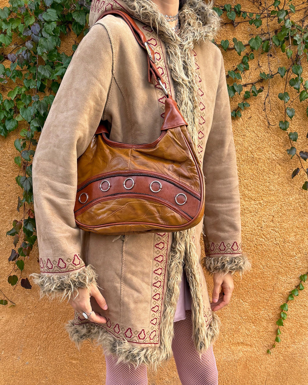 Vintage 2000s brown and mustard-brown faux leather shoulder bag with classic Y2K city-girl appeal. Features metal O-ring details across the front, contrast paneling, and a secure double zip closure. The slouchy silhouette makes it perfect as a bold 2000s statement everyday bag or a party-night accessory. Excellent vintage condition.