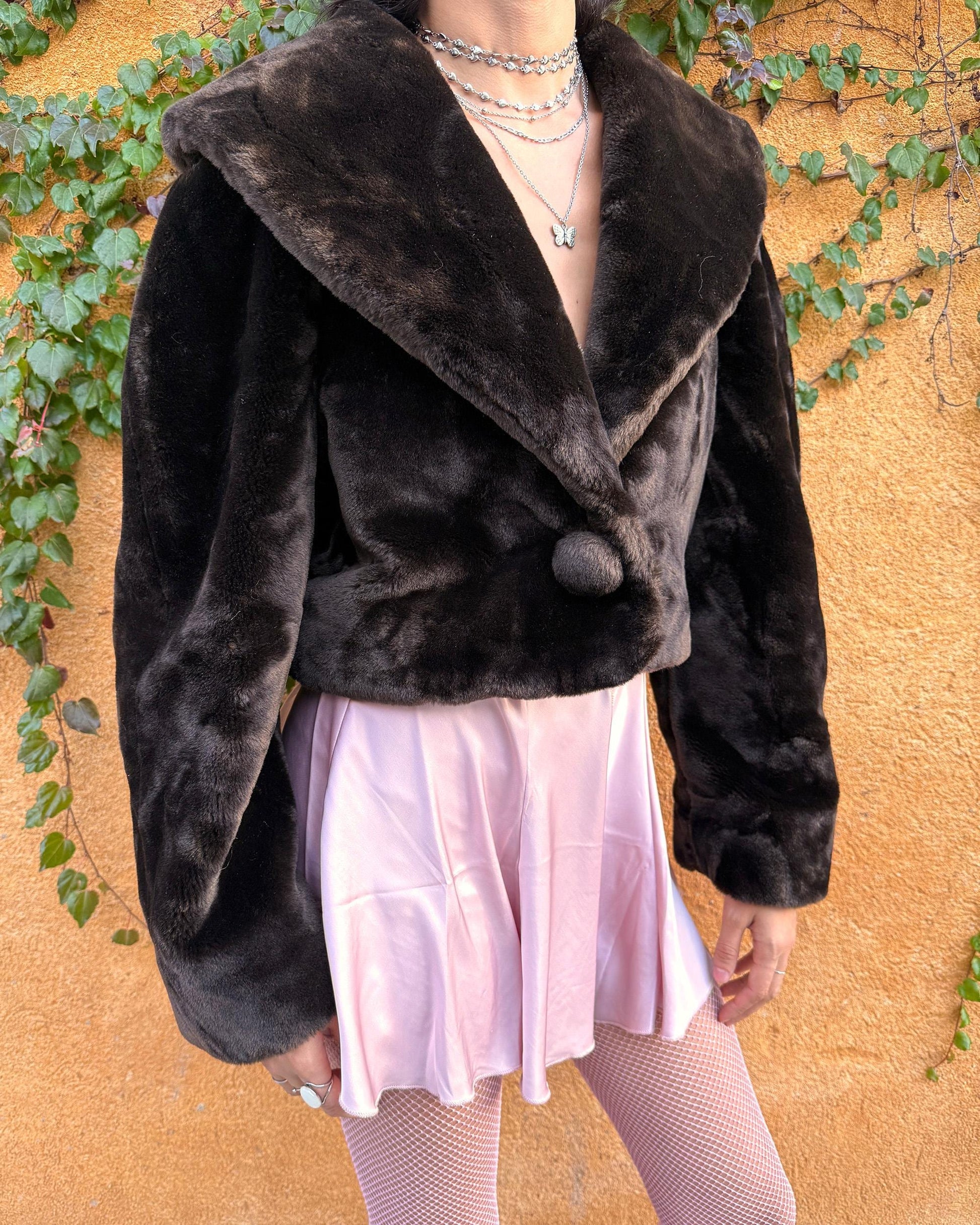 Vintage 90s dark brown faux fur cropped jacket featuring an exaggerated wide collar and a single hook-button closure. Soft, plush, and luxurious, it adds instant elegance to formal winter outfits and is perfect for gala events, prom nights, or refined evening layering. The cropped cut balances the dramatic collar, creating a chic silhouette that elevates dresses or slip styles with minimal effort. Made in Spain. Excellent vintage condition.