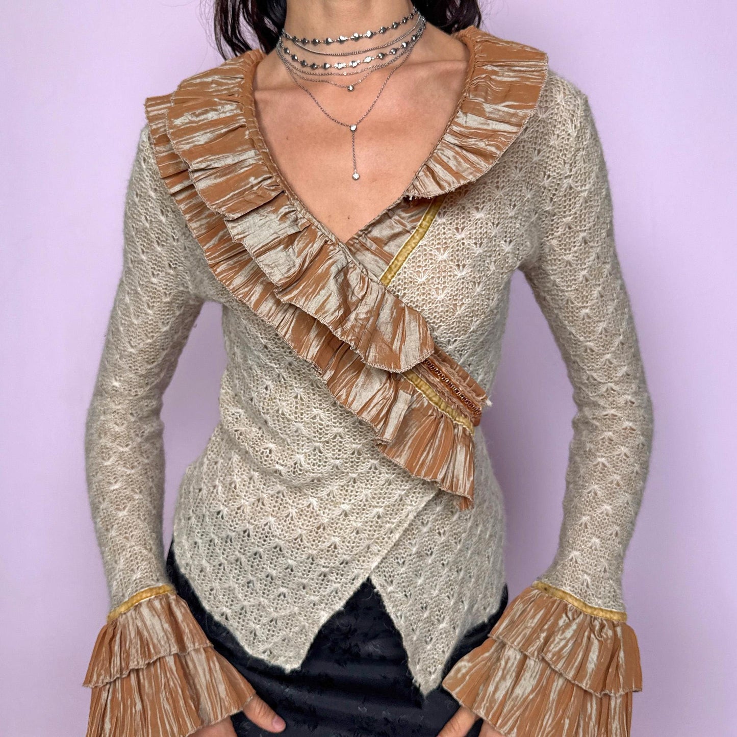 Vintage 2000s beige open-knit wrap cardigan with a dramatic ruffle neckline and tiered mustard-tone ruffle cuffs. Features an elegant tie-back closure, creating a fitted silhouette that highlights the waist. The extravagant design blends romantic, rococo-inspired detailing with a glamorous Y2K formal aesthetic, perfect for event nights, diva moments, or elevated evening styling. Made in France from an acrylic mohair polyester blend. Excellent vintage condition.