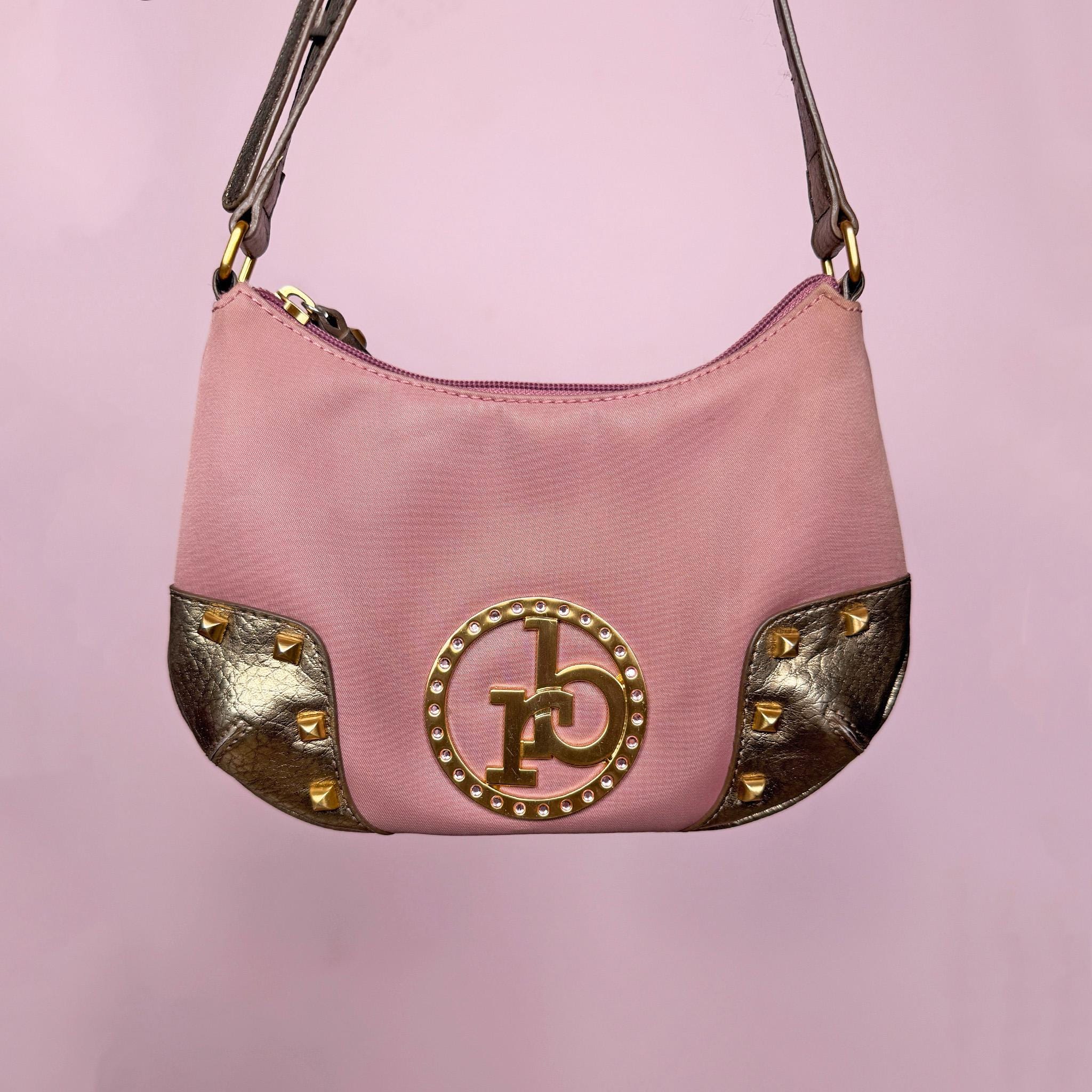 Vintage Y2K dusty muted pink baguette shoulder bag with curved zip top, gold studded corner panels, and a metallic logo with rhinestone detailing at the center front. Features gold hardware, slim shoulder strap, and interior pocket. Iconic Roccobarroco Italian Y2K glam piece for parties and events. Made from polyester. Great vintage condition.