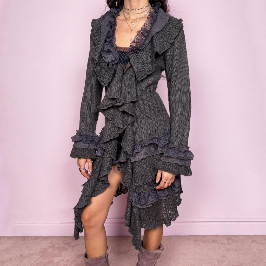 Romantic vintage 2000s gray longline cardigan with dramatic ruffle neckline and lace details. Features bell sleeves with ruffle cuffs, toggle front closure, and asymmetric pointy hem. Whimsical fairycore silhouette with dark baroque rococo style. Stretchy fabric for cozy winter layering. Made from acrylic mohair wool blend. Excellent vintage condition.