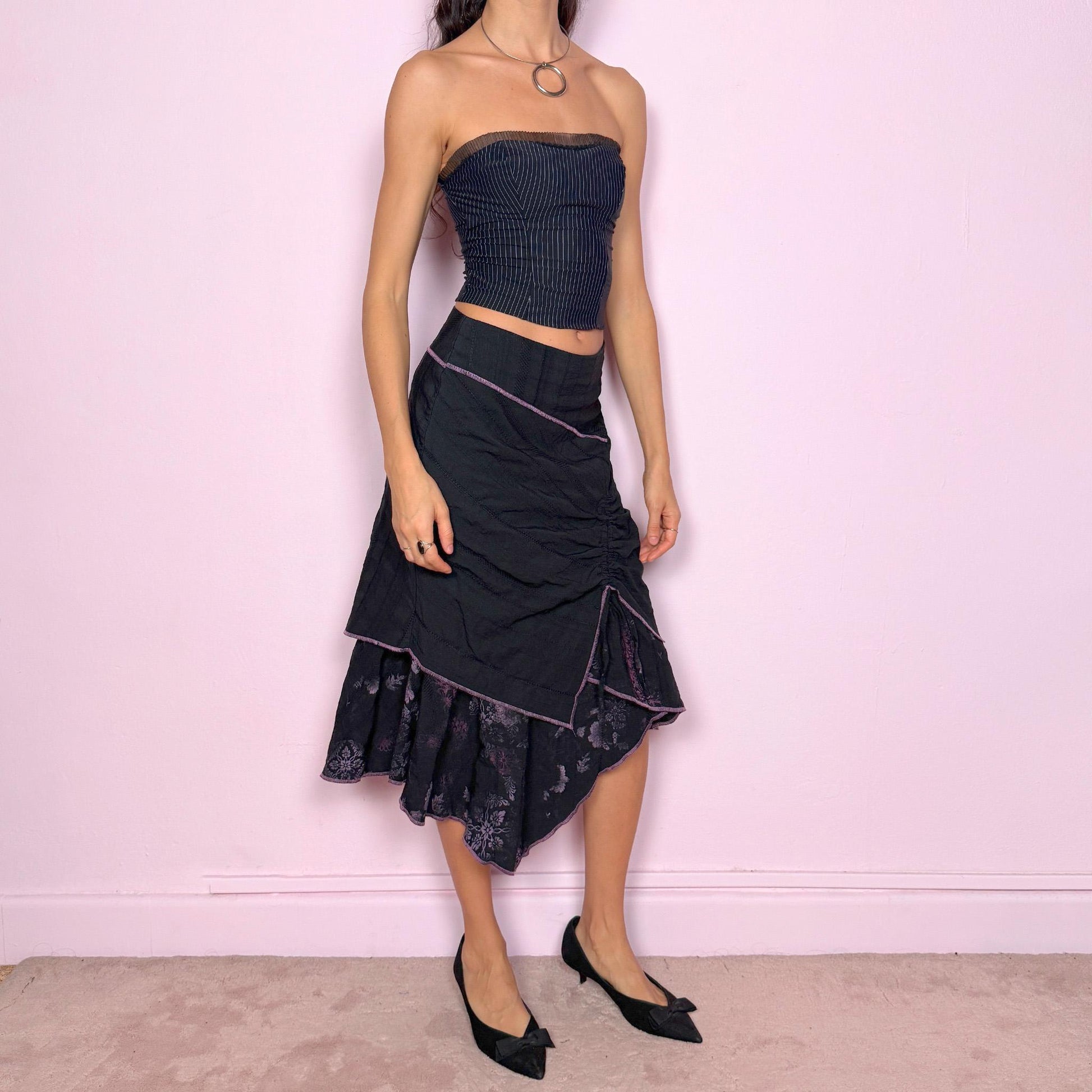 Vintage 2000s black midi skirt with deconstructed avant-garde design, featuring ruched tie drawstring front, layered construction, and ruffle hem. Structured no-stretch fit with back zip closure, ideal for witchy grunge, cyber futuristic layering, or statement event styling. Can be worn mid to low rise for XXS/XS or high waisted for S. Made in France by a Paris-based brand from a cotton polyester blend. Great vintage condition.