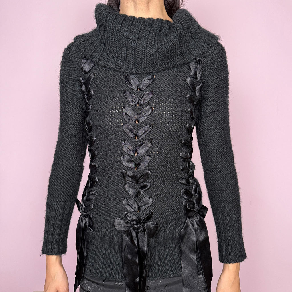 Dark coquette vintage 2000s black turtleneck chunky knit sweater with long sleeves. Features lace-up satin-style ribbon details creating a romantic, unique statement design. Soft yet structured with a fitted silhouette, perfect for winter layering or styled as a standout piece. Stretchy 60% acrylic and 40% wool blend made by a French brand. Great vintage condition.