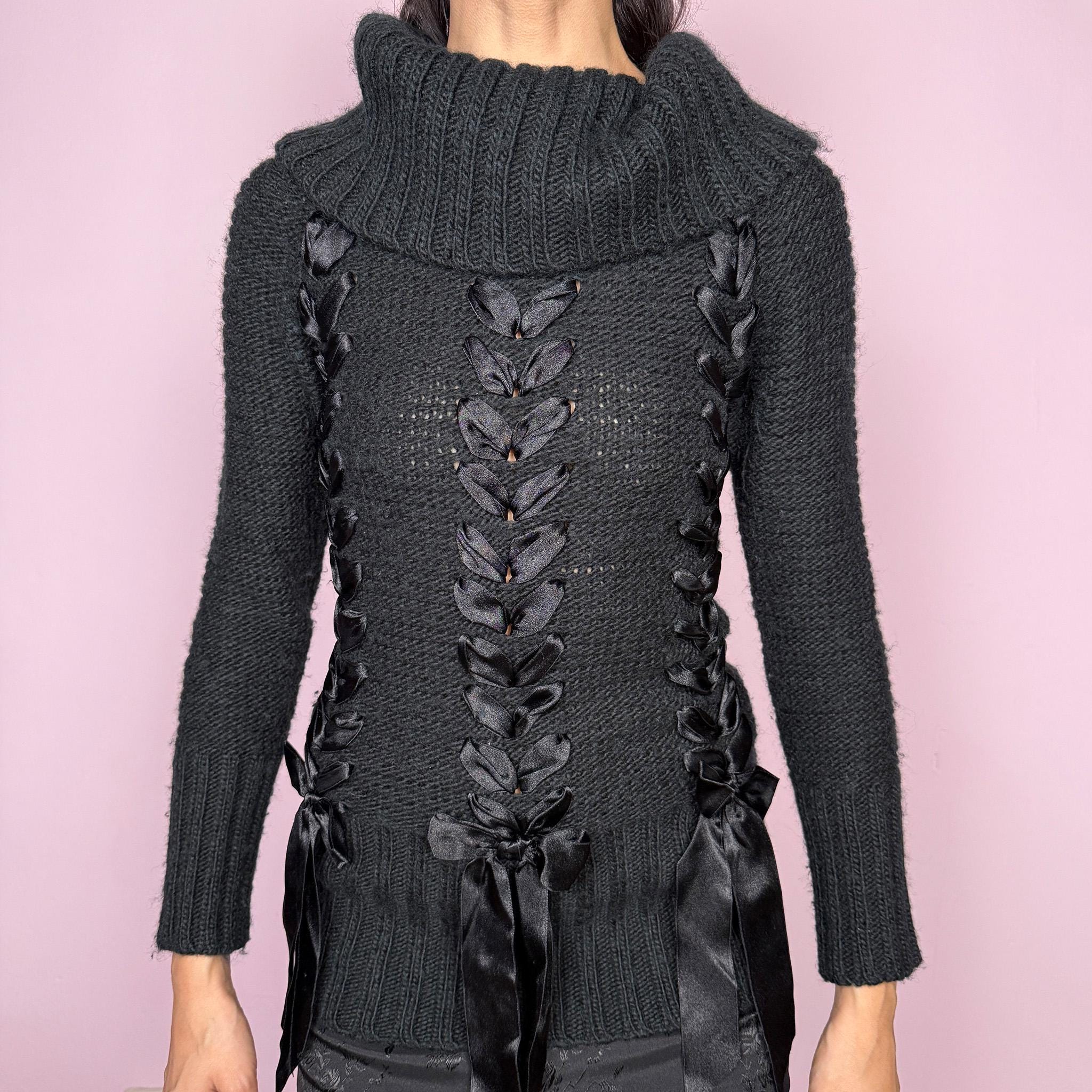 Dark coquette vintage 2000s black turtleneck chunky knit sweater with long sleeves. Features lace-up satin-style ribbon details creating a romantic, unique statement design. Soft yet structured with a fitted silhouette, perfect for winter layering or styled as a standout piece. Stretchy 60% acrylic and 40% wool blend made by a French brand. Great vintage condition.
