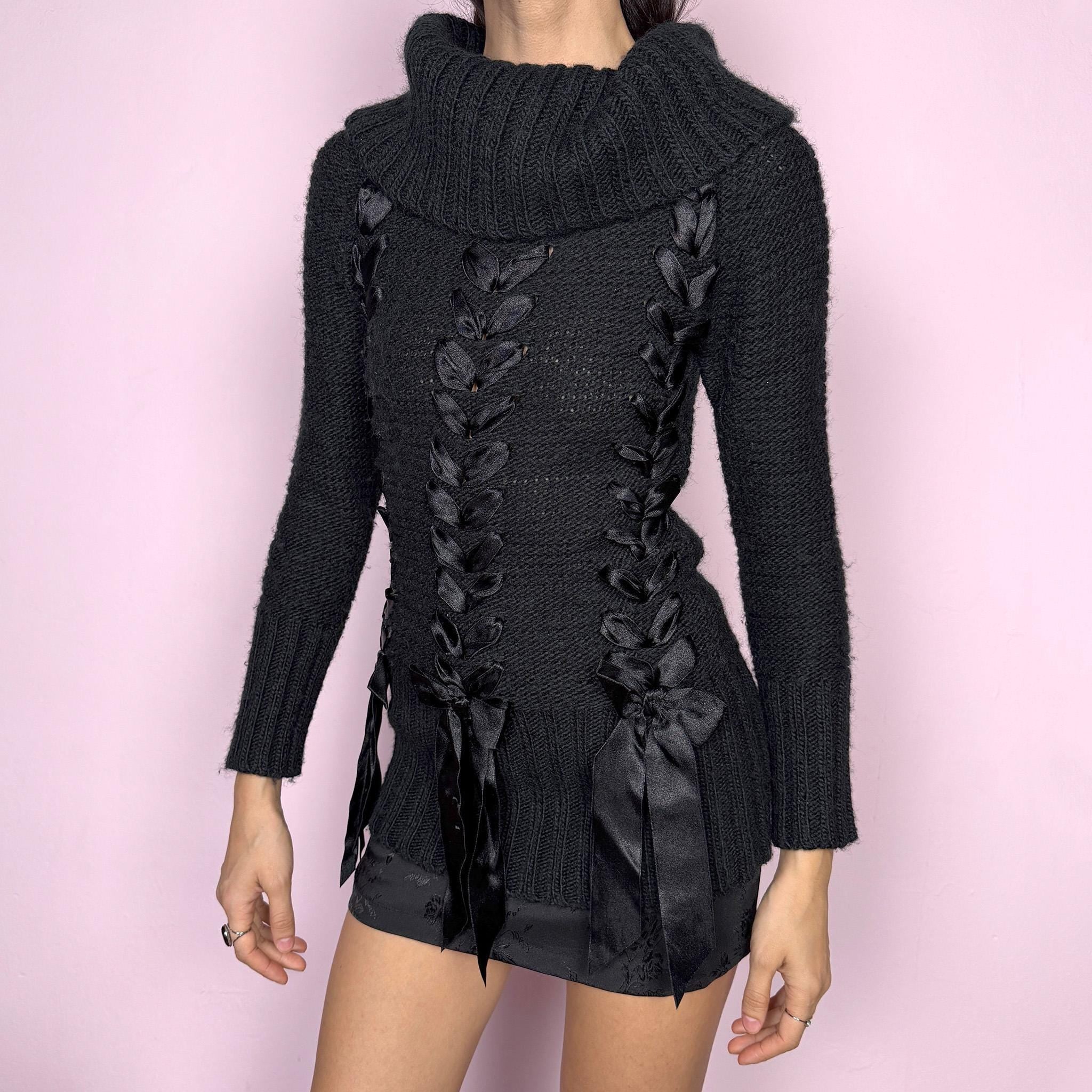 Dark coquette vintage 2000s black turtleneck chunky knit sweater with long sleeves. Features lace-up satin-style ribbon details creating a romantic, unique statement design. Soft yet structured with a fitted silhouette, perfect for winter layering or styled as a standout piece. Stretchy 60% acrylic and 40% wool blend made by a French brand. Great vintage condition.
