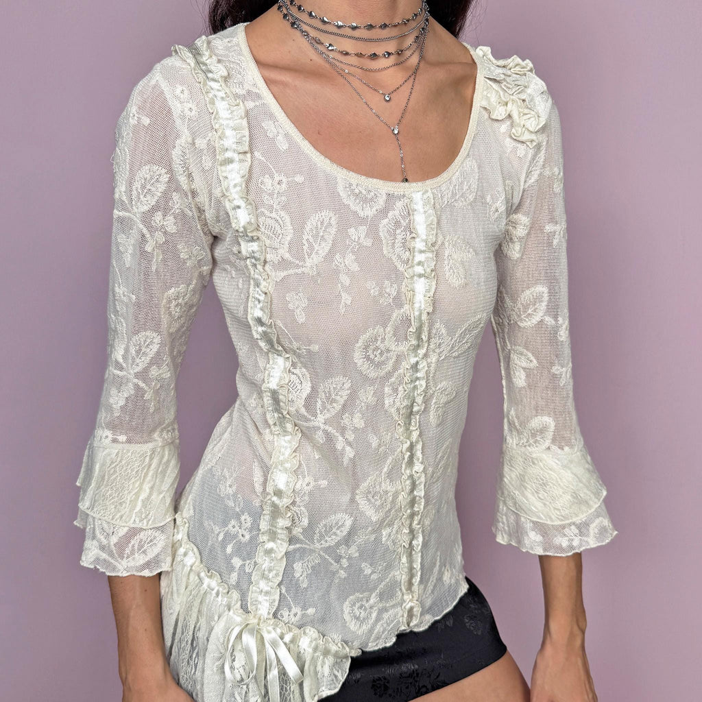 Soft romantic vintage 2000s cream white mesh blouse with floral embroidered details. 3/4 bell sleeves with ruffle cuffs, ruffle gathered seams, lace accents, and an asymmetric hem for an ethereal fairycore look. Statement blouse ideal for whimsical summer events. Stretchy fabric, 60% cotton and 40% polyester. Made in France by a French brand. Excellent vintage condition.