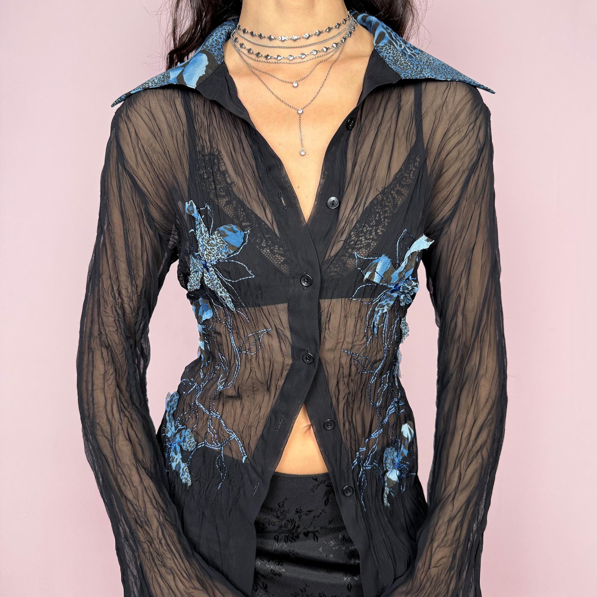 Elegant vintage 2000s black sheer longline blouse featuring blue floral embroidered appliqués with subtle leopard print, flared long sleeves, collared neckline, and side slits. Button-down front perfect for party nights or formal evening events. By French brand. Excellent vintage condition.