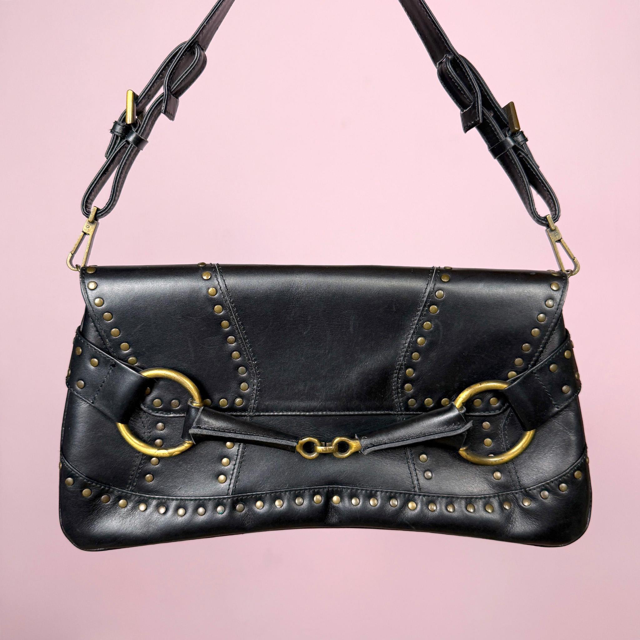 Stunning vintage early 2000s black studded shoulder bag by Lorenzo Coll. Genuine leather construction with bold Y2K silhouette, gold-tone brass hardware, large O-ring front details, adjustable strap, and magnetic snap button closure. Ideal for going out. Made in Spain. Excellent vintage condition.