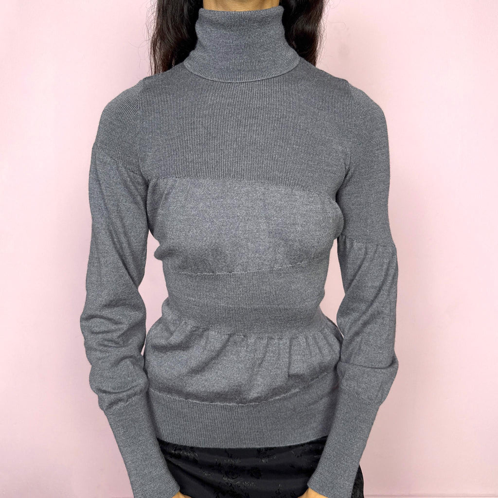 Avant garde vintage 2000s Italian designer gray turtleneck sweater by Moschino Cheap and Chic, crafted from 100% virgin wool and made in Italy. Sculptural knit design with ballooned panels contrasted by fitted sections, creating subtle volume and structure. Clean design typical of Moschino’s early-2000s tailoring, where quality materials and sharp construction took priority over graphics. Perfect for minimal 90s, office siren, or elevated everyday styling. Excellent vintage condition.