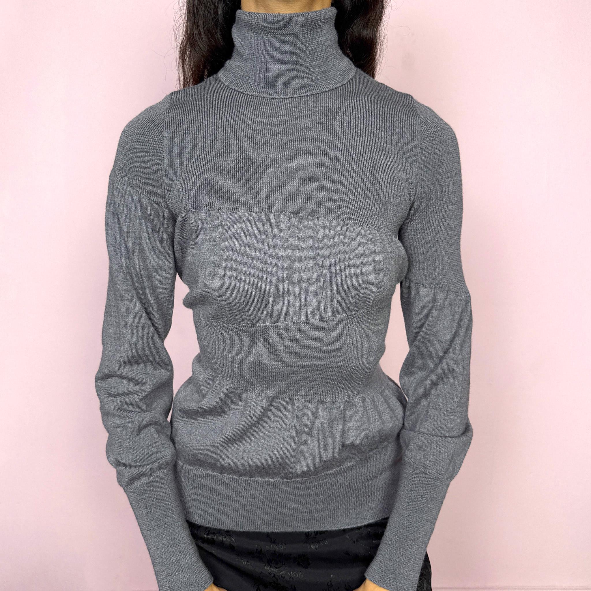 Avant garde vintage 2000s Italian designer gray turtleneck sweater by Moschino Cheap and Chic, crafted from 100% virgin wool and made in Italy. Sculptural knit design with ballooned panels contrasted by fitted sections, creating subtle volume and structure. Clean design typical of Moschino’s early-2000s tailoring, where quality materials and sharp construction took priority over graphics. Perfect for minimal 90s, office siren, or elevated everyday styling. Excellent vintage condition.
