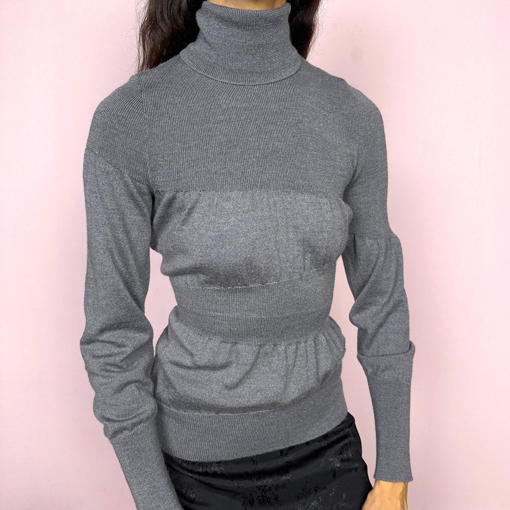 Avant garde vintage 2000s Italian designer gray turtleneck sweater by Moschino Cheap and Chic, crafted from 100% virgin wool and made in Italy. Sculptural knit design with ballooned panels contrasted by fitted sections, creating subtle volume and structure. Clean design typical of Moschino’s early-2000s tailoring, where quality materials and sharp construction took priority over graphics. Perfect for minimal 90s, office siren, or elevated everyday styling. Excellent vintage condition.