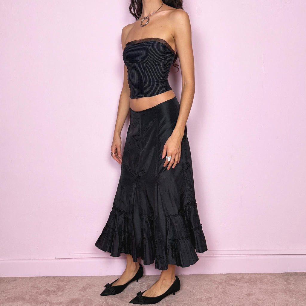 Vintage 2000s black elegant midi skirt featuring a godet-style silhouette with pleated ruffle panels creating a fluid asymmetric flare. Back zip closure with no stretch. Avant garde dark romantic aesthetic, perfect for event, party, or formal wear. Can be worn mid rise for size S or high waisted for size M. Made by a French brand. Great vintage condition.