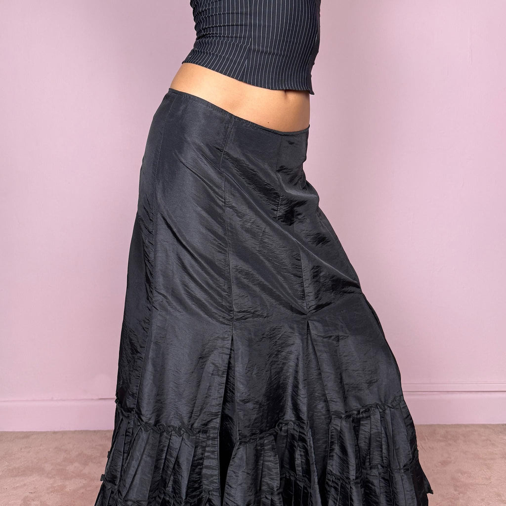 Vintage 2000s black elegant midi skirt featuring a godet-style silhouette with pleated ruffle panels creating a fluid asymmetric flare. Back zip closure with no stretch. Avant garde dark romantic aesthetic, perfect for event, party, or formal wear. Can be worn mid rise for size S or high waisted for size M. Made by a French brand. Great vintage condition.