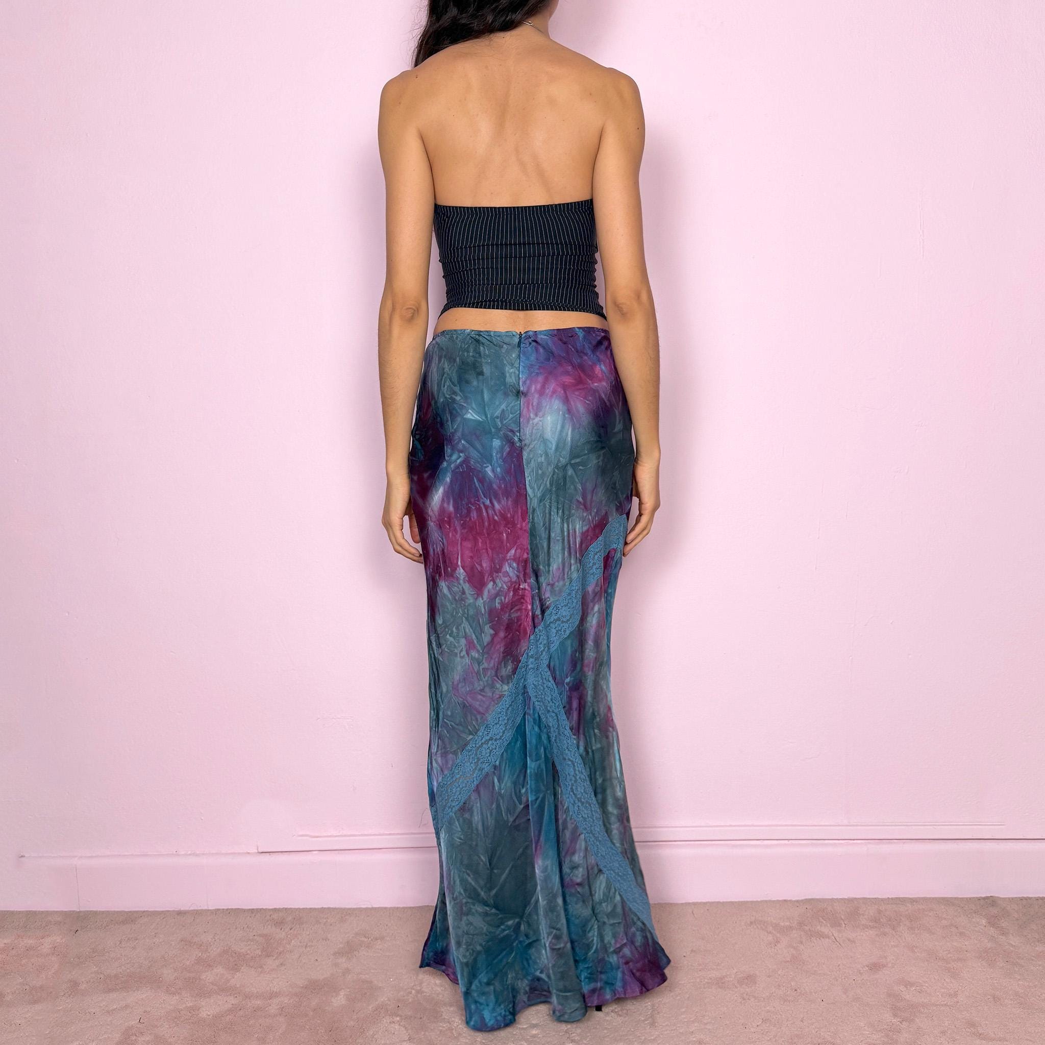 Vintage 2000s blue and purple tie dye midi skirt in a flowy bias cut slip silhouette with a soft, draped fit. Features a unique asymmetric lace panel detail, back zip closure, and fluid movement. From Kenzo Jeans, the brand’s early 2000s diffusion line known for its playful prints and fluid, feminine silhouettes. Perfect for summer, arty gallery girl looks, or vacation styling, a bold yet wearable statement piece. Can be worn mid rise for size XS or high waisted for size S.