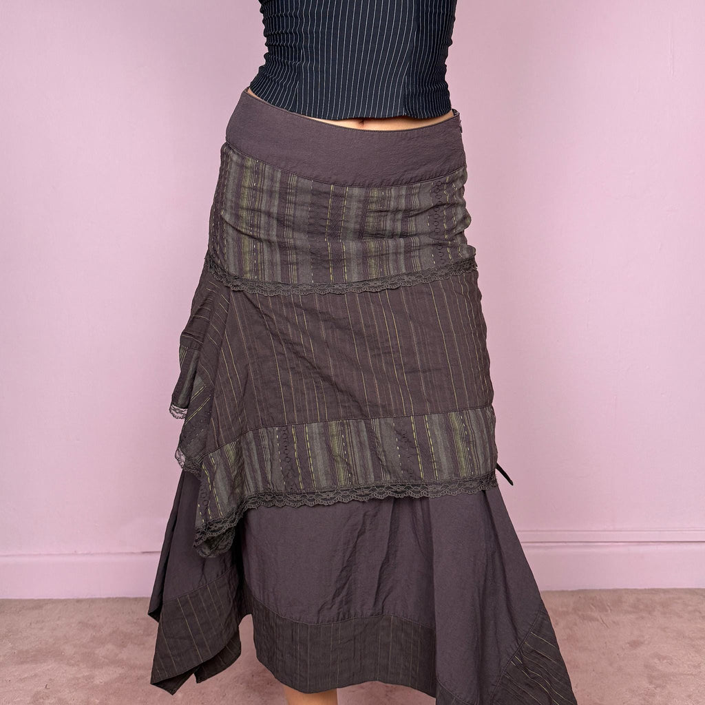 Vintage 2000s dark brown asymmetric midi skirt with an avant garde deconstructed layered design, featuring striped panels with subtle green lines, lace trim, and tie drawstring side details. Side zipper closure with no stretch. Fairy grunge aesthetic. Can be worn high waisted for size S or worn lower on the waist for size XS/XXS. Made by a French brand from a cotton polyester polyamide blend. Great vintage condition.