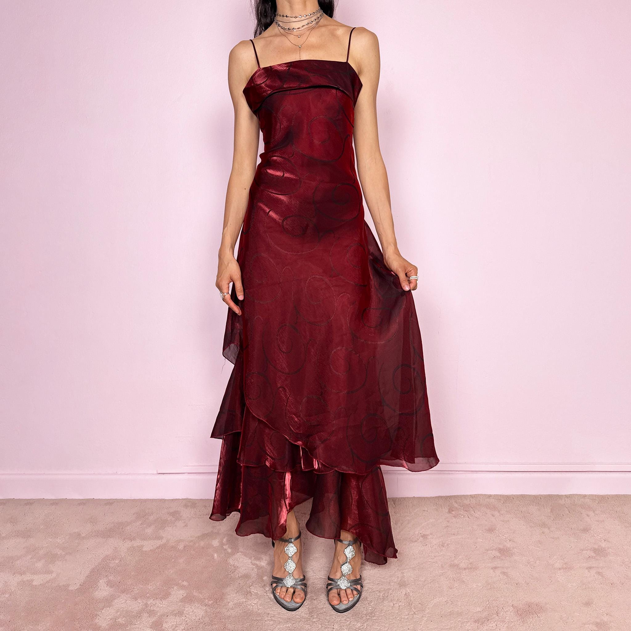 Vintage 2000s statement burgundy midi dress with iridescent shimmer and elegant layered construction. Features spaghetti straps, asymmetrical tiered hem and sheer overlay with swirl pattern. Fluid body-skimming fit with romantic movement, perfect for evening events or occasionwear. Made in France from a polyester elastane blend. Excellent vintage condition.