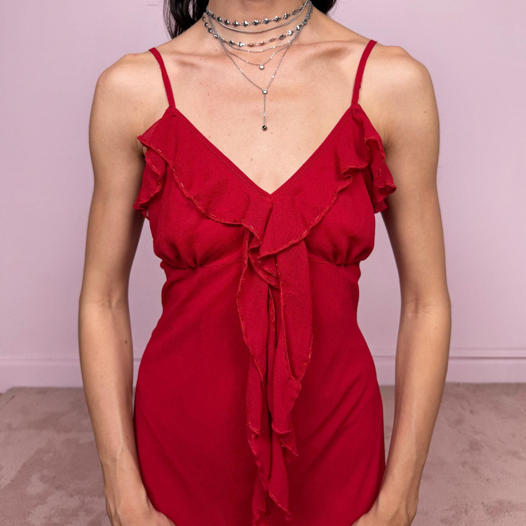 Vintage 2000s romantic red midi dress with a flattering V neckline and adjustable straps. Features delicate ruffle detailing at the bust, subtle beaded accents and an asymmetrical layered ruffle hem for fluid movement. Body-skimming fit with a dreamy coquette feel, perfect for summer parties or date nights. Great vintage condition.
