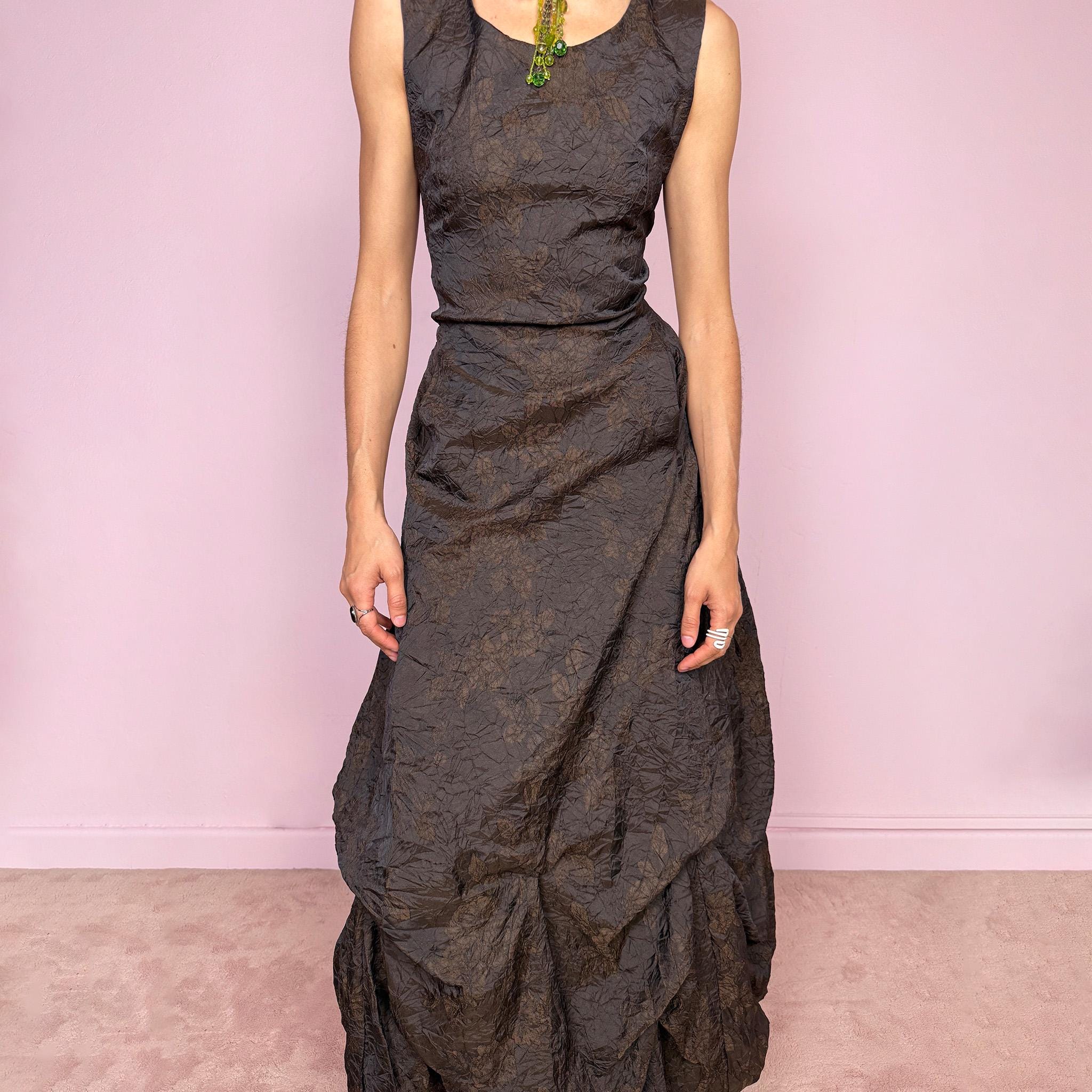 Vintage 90s dark brown sleeveless midi dress with a crinkle texture and subtle floral pattern. Features a voluminous draped balloon bubble hem and lace-up back for a fitted silhouette. Non-stretch design with avant-garde formal elegance, perfect for night events or statement evenings. Made in France from 50% acetate and 50% polyester. Excellent vintage condition.
