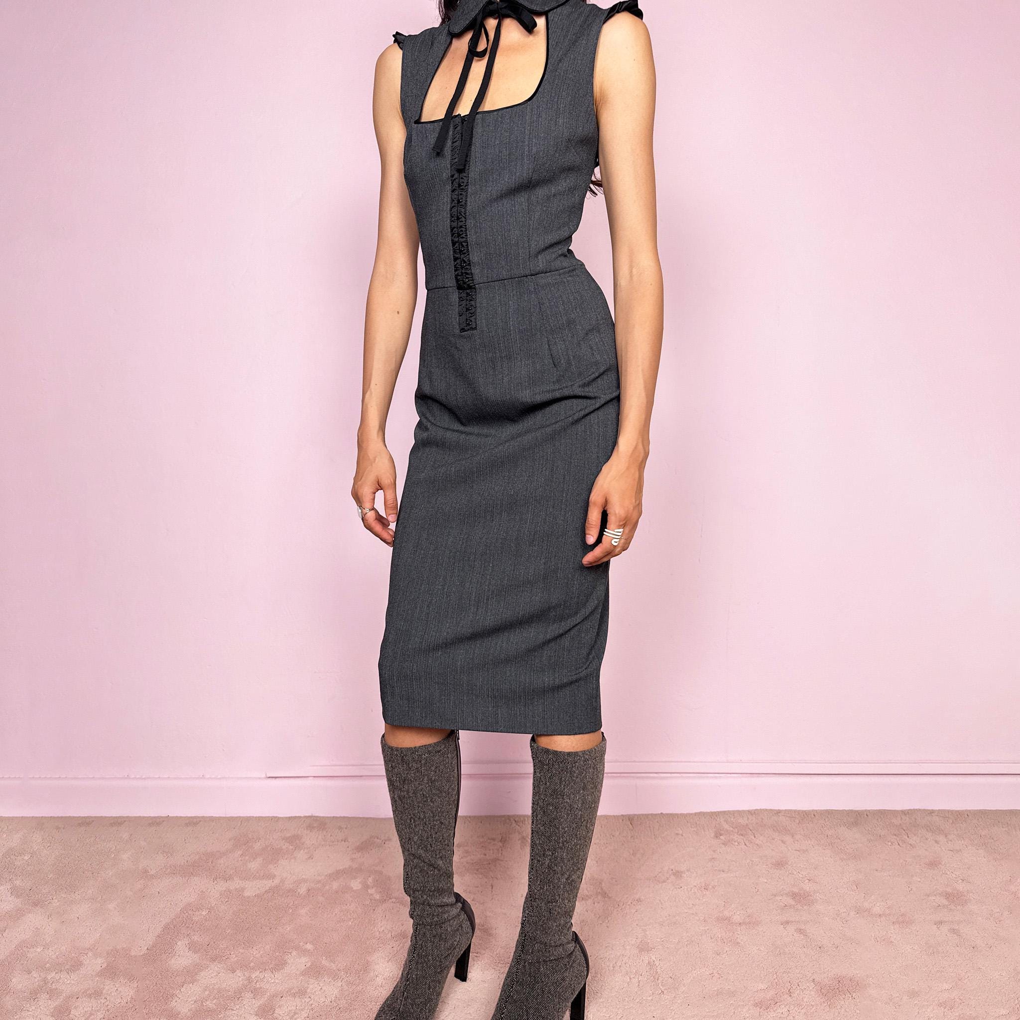 Vintage 2000s minimal preppy Dolce & Gabbana fitted pencil midi dress in gray tailoring fabric with slight stretch. Sculpted body-skimming silhouette with dramatic square cut out neckline, rounded collar with tie detail, subtle ruffled cap sleeves, front hook eye closure and side zip closure. Flattering secretary siren meets dark academia aesthetic. Made from a polyester viscose elastane blend with 97% silk lining. Excellent vintage condition.