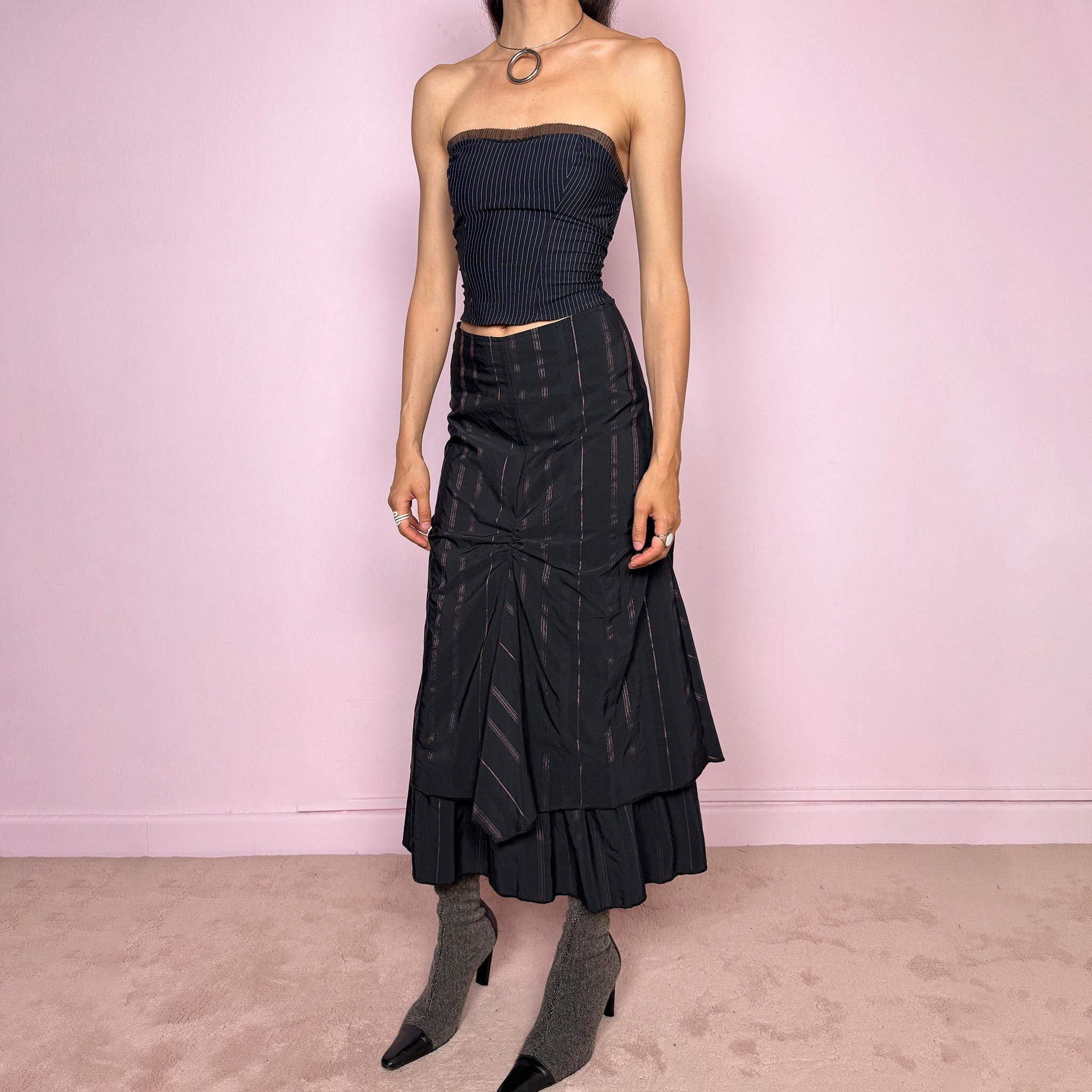 Vintage 2000s black midi skirt with pink pinstripes, a layered deconstructed silhouette, ruched details, and ruffled hem. This dark avant-garde piece has a structured no-stretch fit with back zip closure. Can be worn high waisted for size S or lower rise for XXS and XS. Made in France from a cotton, polyamide, and polyester blend. Great vintage condition.