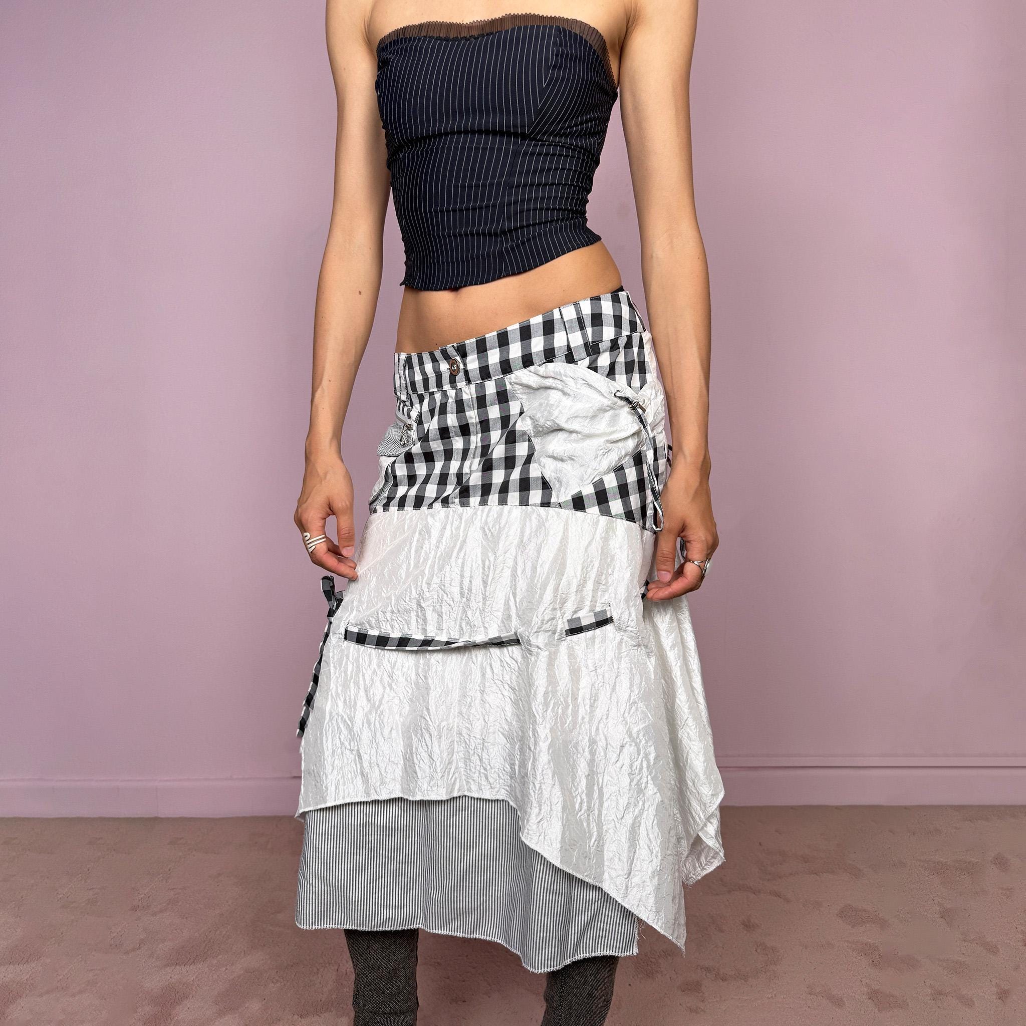 Vintage 2000s white and black midi skirt with deconstructed avant-garde styling, plaid panels, pockets, front zip closure, tie detail, and an asymmetric layered hem with crinkled texture and a striped underlayer. Extravagant artistic statement piece with a rag doll silhouette. Can be worn high waisted for size M or lower rise for sizes XS and S. Made from a polyester and polyamide blend. Great vintage condition.