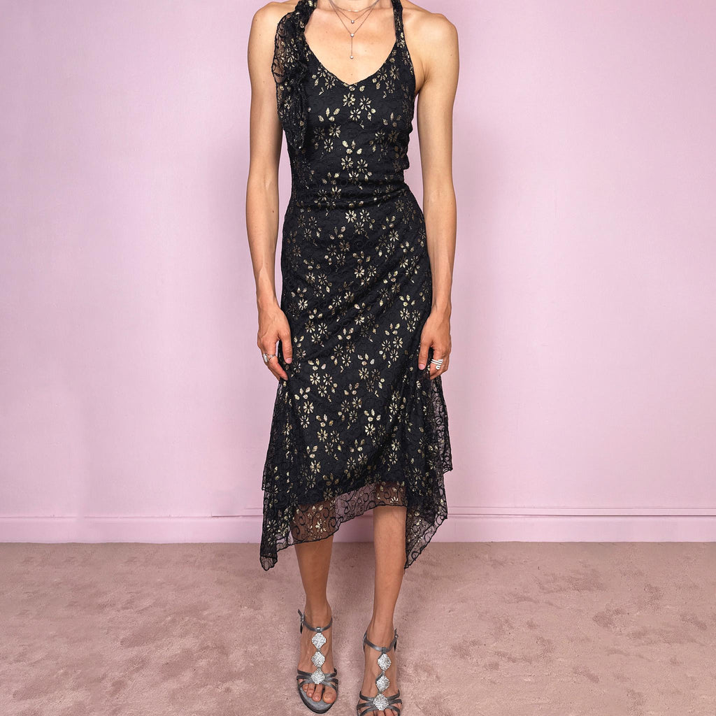 Vintage 2000s black backless halter midi dress with a V neckline, stretchy fit, asymmetric handkerchief hem, and lace mesh overlay with a gold floral pattern. Dark romantic statement piece for parties, nights out, or elegant evening events. Made by a Spanish designer. Excellent vintage condition.