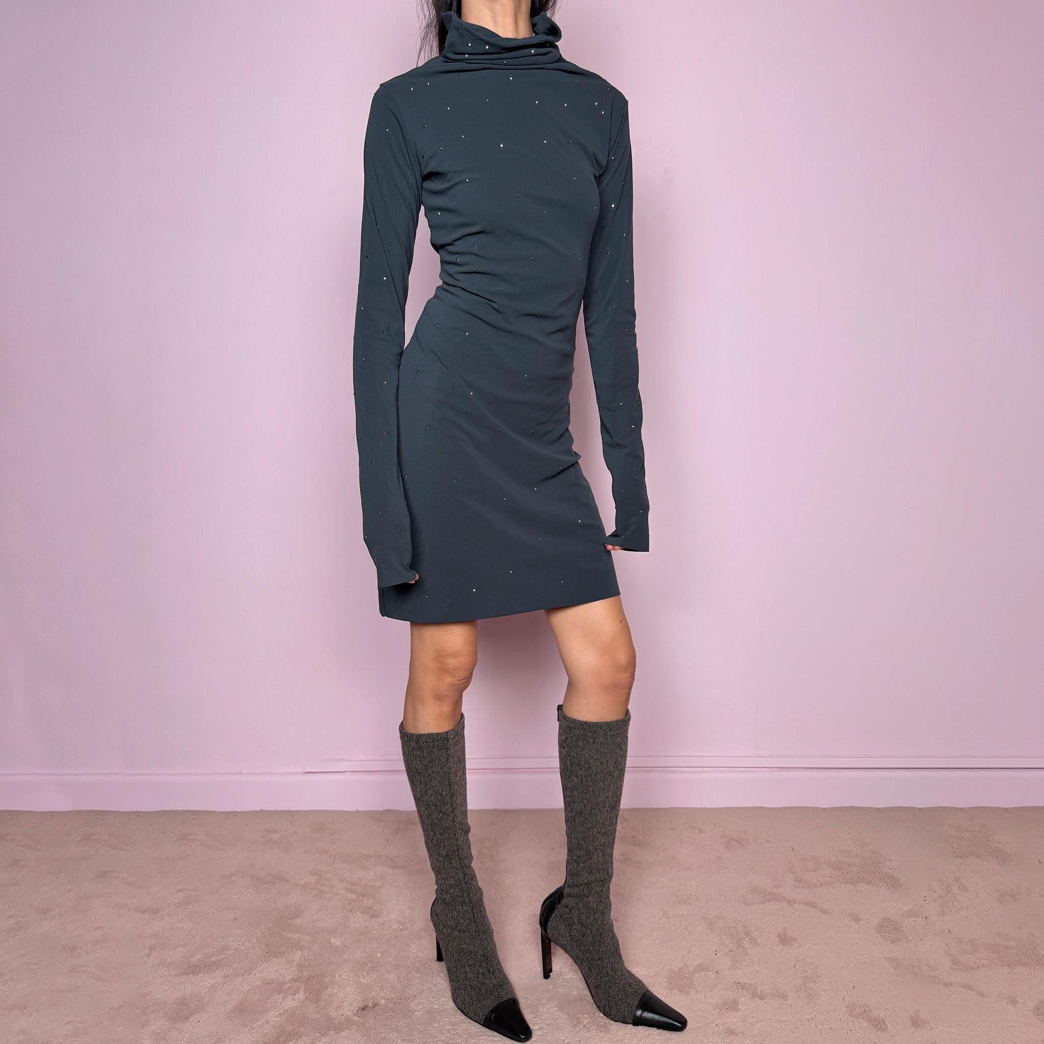 Vintage 2000s gray mini dress made in Italy from a stretchy polyamide-elastane mesh fabric. Features long sleeves, a draped high neckline, a body-skimming silhouette that flares at the hem, and delicate mini studded details throughout. A sleek dark minimal Y2K piece with an avant-garde feel. Excellent vintage condition.