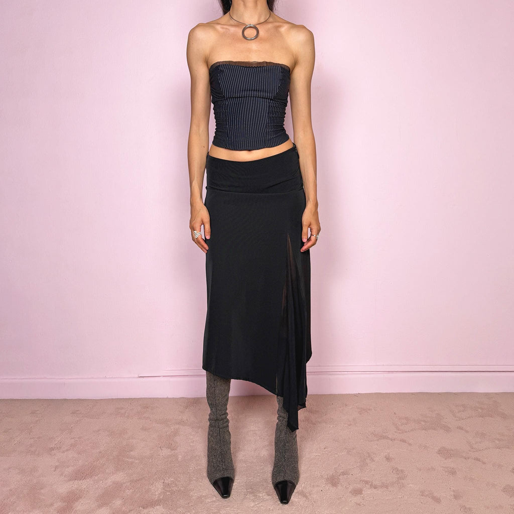 Vintage 2000s black midi skirt with an avant-garde deconstructed look. Features a pointed asymmetric hem, semi-sheer mesh panel detail, side zip closure, and a smooth no-stretch fit with a fluid draped silhouette. Perfect for dark styling and evening events. Can be worn high waisted for S or lower rise for XS/XXS. Made from a polyester elastane blend. Excellent vintage condition.