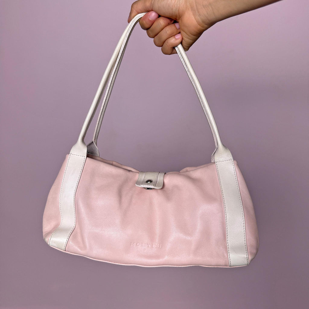 Vintage 2000s Montini pink genuine leather shoulder bag. Features a soft Y2K baguette-inspired silhouette, full top zip closure, magnetic snap button closure, white leather shoulder straps, silver-tone stud details, and a decorative jeweled front strap with faux pearl and pink rhinestone accents. Compact yet eye-catching, with a soft, feminine, and playful 2000s rococo coquette aesthetic. Made in Italy.