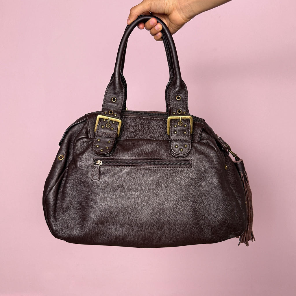 Vintage 2000s brown genuine leather shoulder bag. Features a large bowling-style silhouette, top zip closure, double handles, antique gold-tone studs, metal eyelets, and buckle details throughout. A bold Y2K Italian leather statement bag with a biker-boho grunge glam feel, spacious enough for everyday use while still feeling unique and visually strong. Excellent vintage condition.