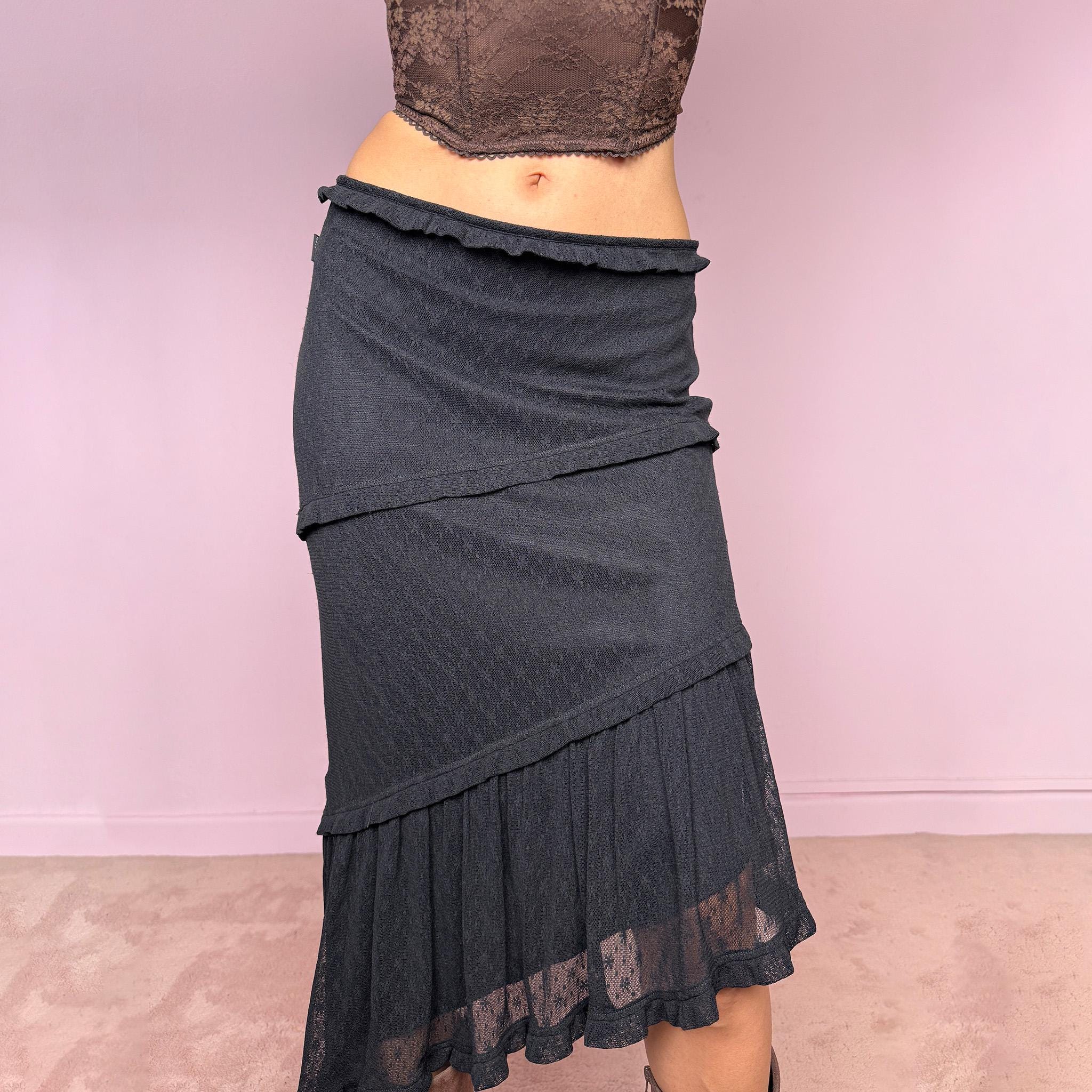 Vintage 2000s Moschino Jeans black lace asymmetric midi skirt made in Italy from a stretchy polyamide fabric. Features a low-rise, soft stretch waistband without elastic, delicate ruffle trim, layered asymmetric panels, and a sheer lace pleated hem. A dark romantic Y2K designer piece, perfect for elevated evening looks. Excellent vintage condition.