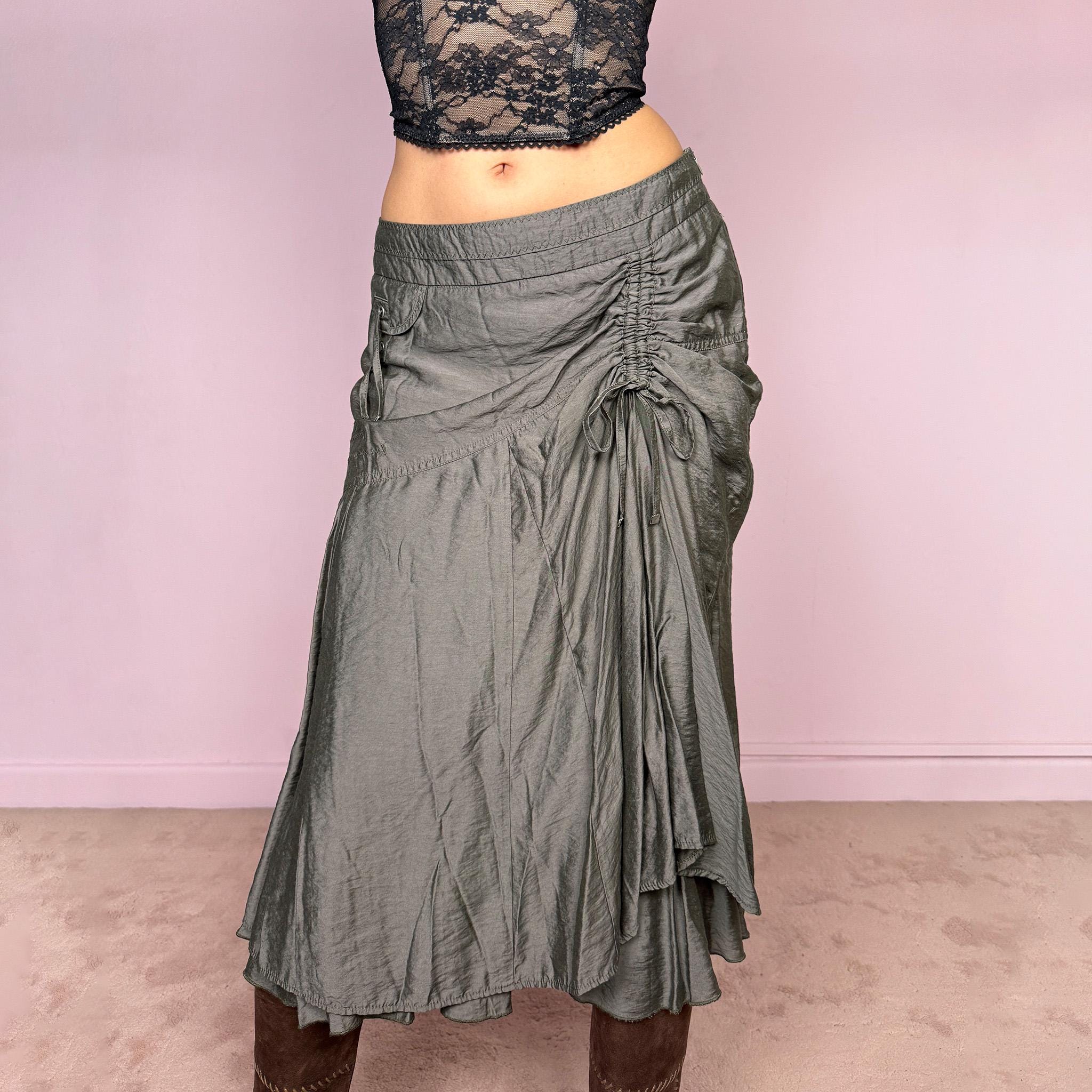 Vintage 2000s greenish-gray layered midi skirt featuring a fluid draped silhouette, ruched side detail with tie accents, and a softly flared layered hem. Designed in a non-stretch 83% viscose-blend fabric with a side zip closure and full polyester lining, the skirt has an avant-garde deconstructed aesthetic. Can be worn high-waisted for size L or lower-rise for M. Great vintage condition.