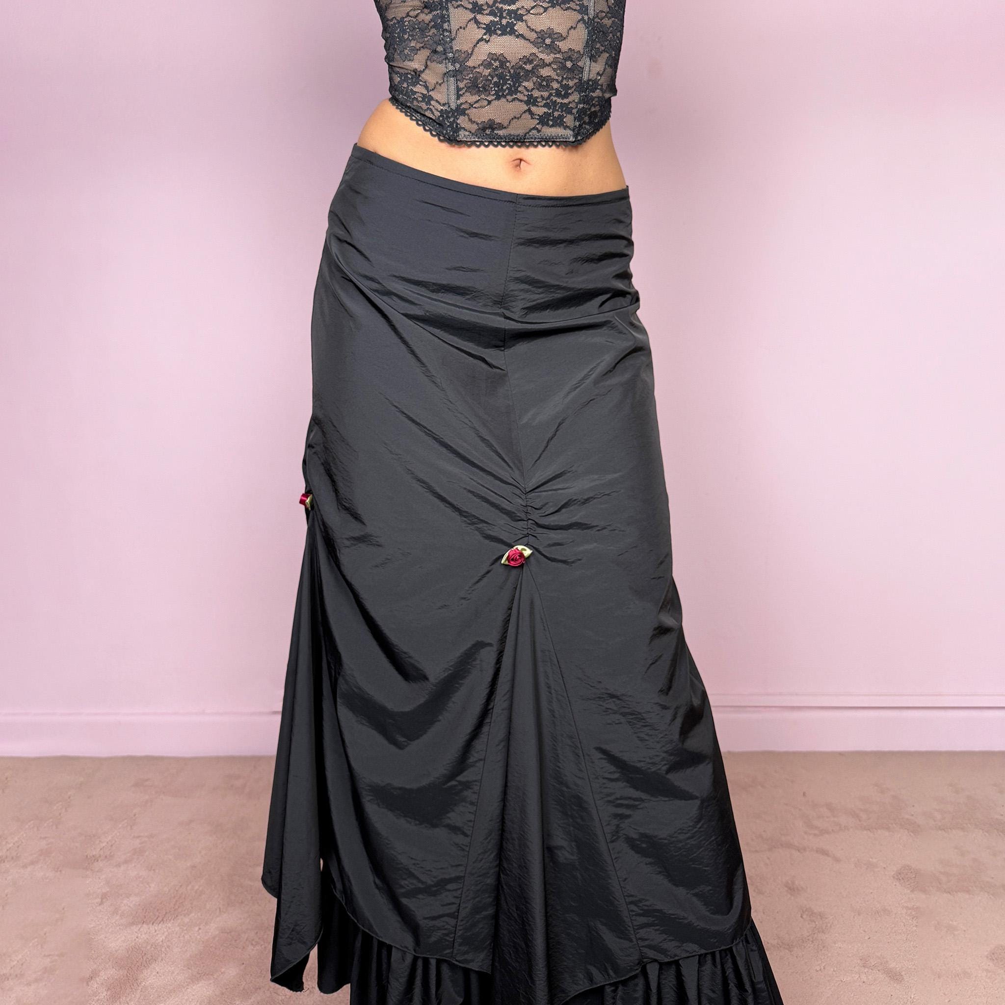 Vintage 2000s black layered ruched midi skirt with a dark gothic avant-garde feel. Back zip closure, structured non-stretch fabric, gathered front ruching, asymmetric layered paneling, ruffled hem, and small floral details. Can be worn high waisted for M or lower rise for S and XS. Made from 100% polyamide with lining 100% polyester. Excellent vintage condition.