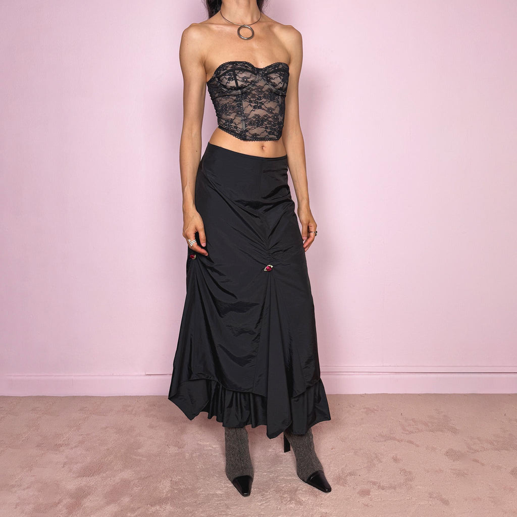 Vintage 2000s black layered ruched midi skirt with a dark gothic avant-garde feel. Back zip closure, structured non-stretch fabric, gathered front ruching, asymmetric layered paneling, ruffled hem, and small floral details. Can be worn high waisted for M or lower rise for S and XS. Made from 100% polyamide with lining 100% polyester. Excellent vintage condition.