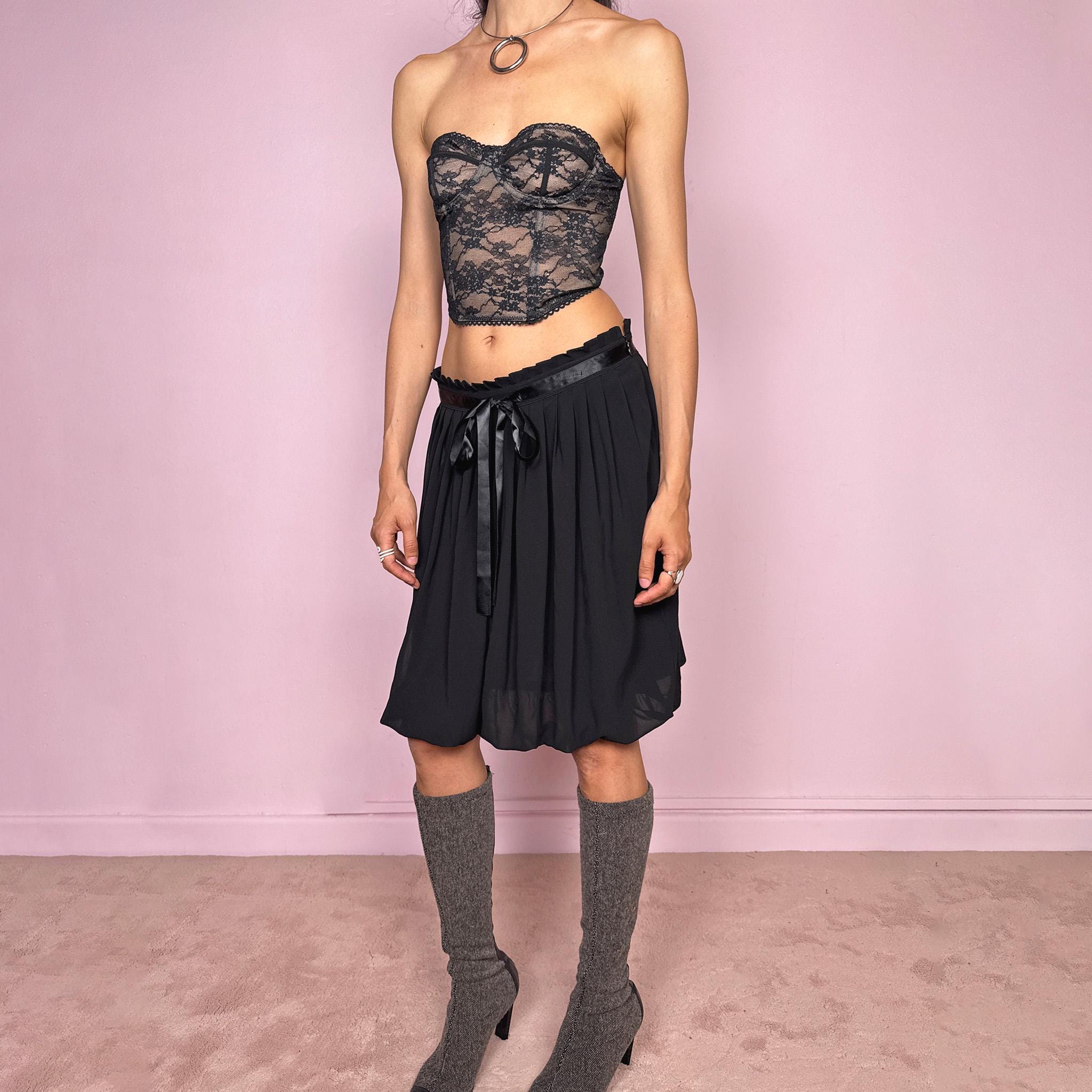 Vintage 2000s black bubble hem midi skirt featuring a pleated silhouette with side zip closure, front tie detail, and voluminous bubble hem. Romantic yet minimal with a subtle coquette party mood, ideal for formal occasions, evening looks, or darker feminine everyday styling. Can be worn high waisted for M or lower rise for S. From a French brand. Excellent vintage condition.