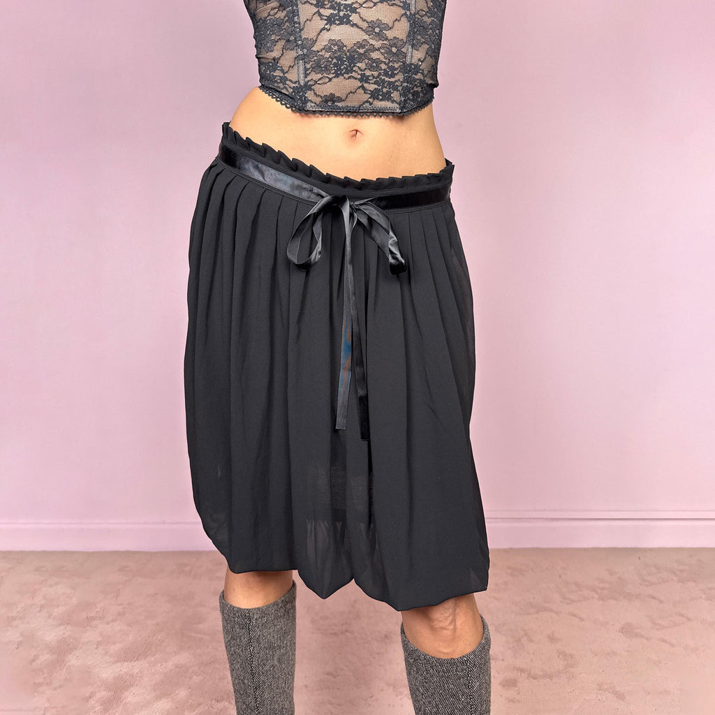 Vintage 2000s black bubble hem midi skirt featuring a pleated silhouette with side zip closure, front tie detail, and voluminous bubble hem. Romantic yet minimal with a subtle coquette party mood, ideal for formal occasions, evening looks, or darker feminine everyday styling. Can be worn high waisted for M or lower rise for S. From a French brand. Excellent vintage condition.