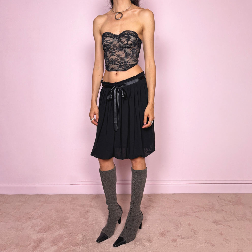 Vintage 2000s black bubble hem midi skirt featuring a pleated silhouette with side zip closure, front tie detail, and voluminous bubble hem. Romantic yet minimal with a subtle coquette party mood, ideal for formal occasions, evening looks, or darker feminine everyday styling. Can be worn high waisted for M or lower rise for S. From a French brand. Excellent vintage condition.