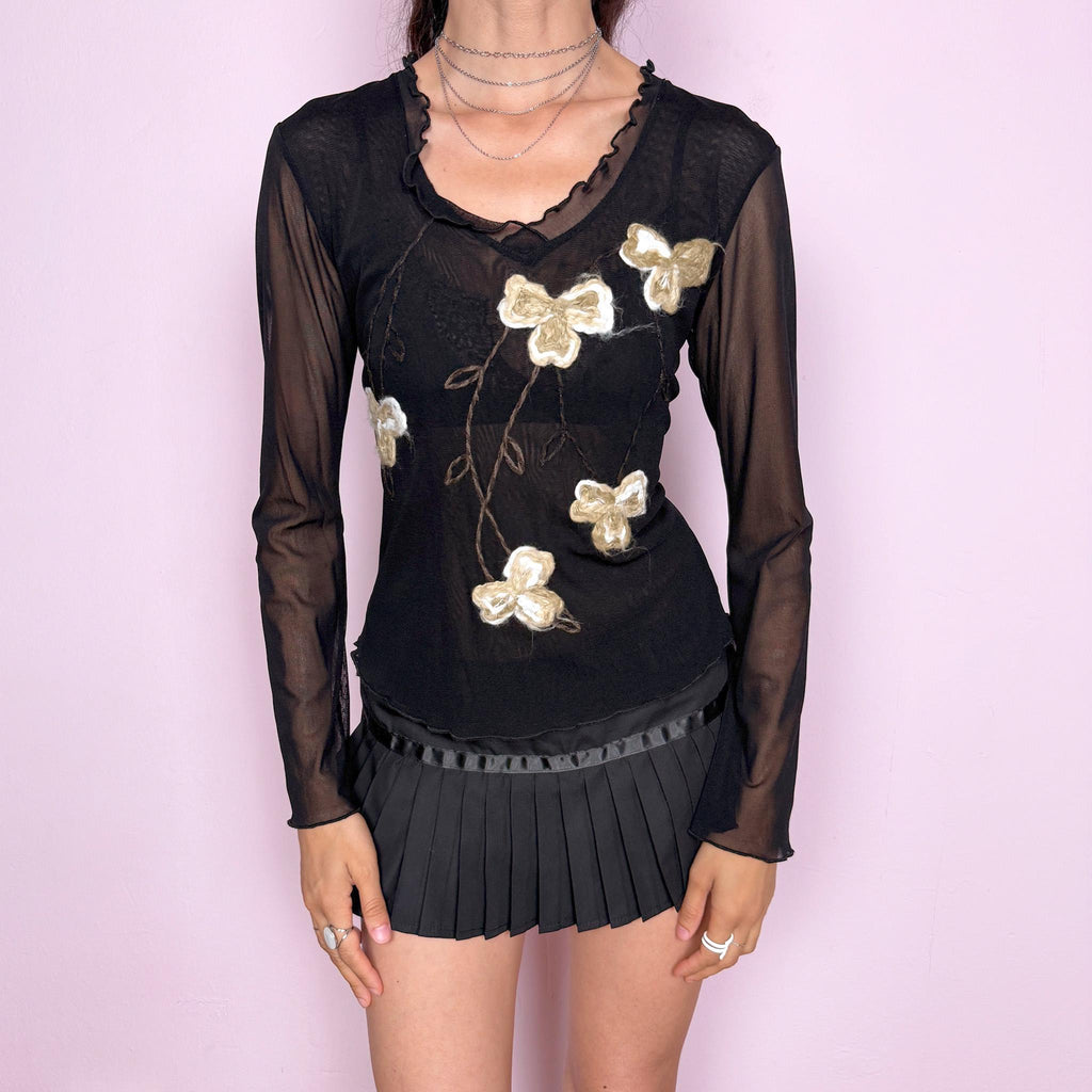 Vintage 2000s black sheer mesh long sleeve top with floral embroidery and textured appliqué details through the front. Fitted stretch mesh silhouette with delicate lettuce trim neckline, flared sleeves, and softly wavy hem. Dark avant-garde Y2K aesthetic with an artisanal floral finish. Excellent vintage condition.