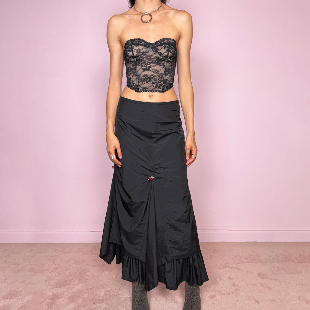 Vintage 2000s black layered ruched midi skirt with a dark gothic avant-garde feel. Back zip closure, structured non-stretch fabric, gathered front ruching, asymmetric layered paneling, ruffled hem, and small floral details. Can be worn high waisted for M or lower rise for S and XS. Made from 100% polyamide with lining 100% polyester. Excellent vintage condition.